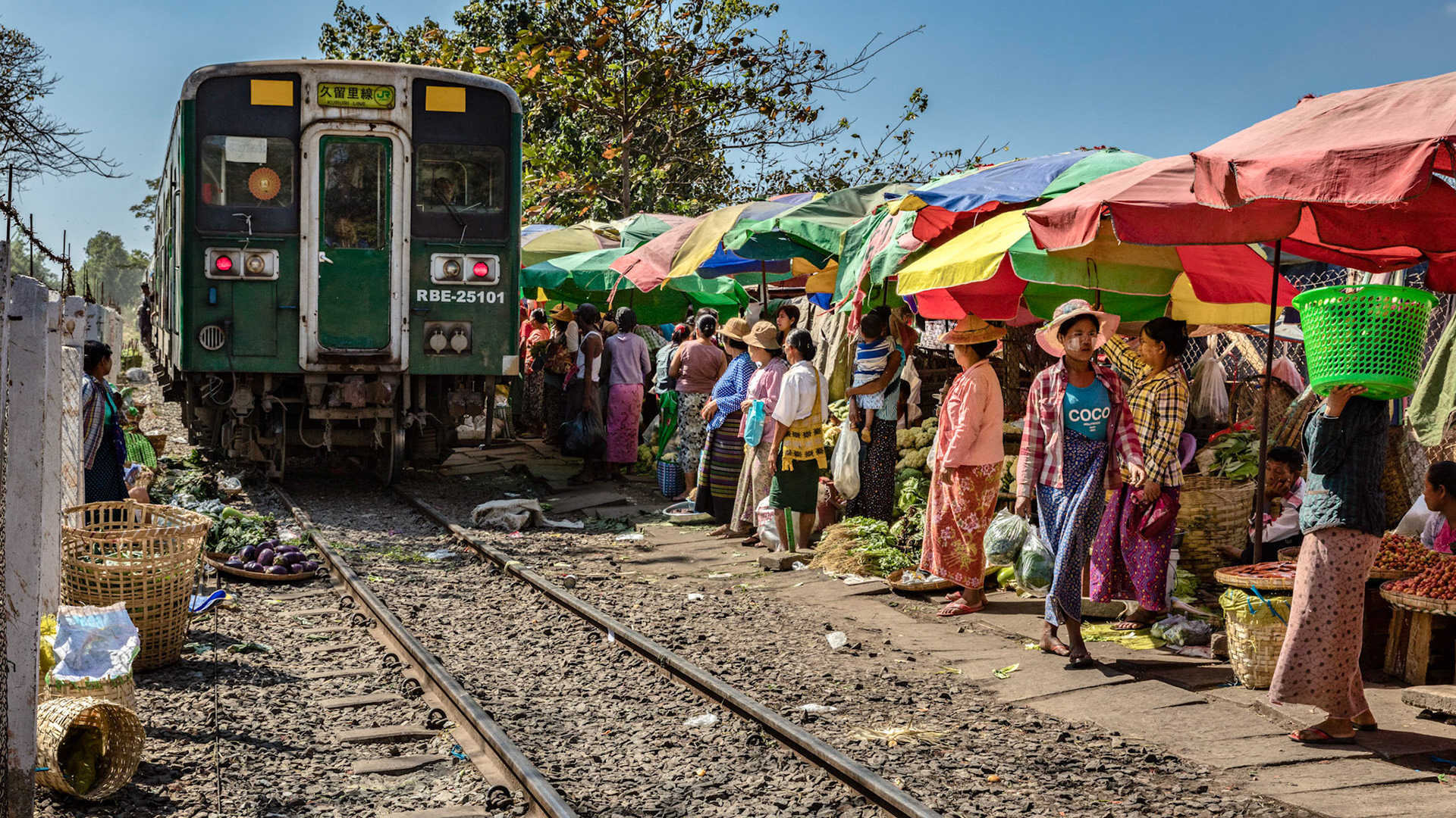 Burmese locals moving out of the way of a train as it pulls up to the station at the Da Nyin Gone market in Yangon, Myanmar.