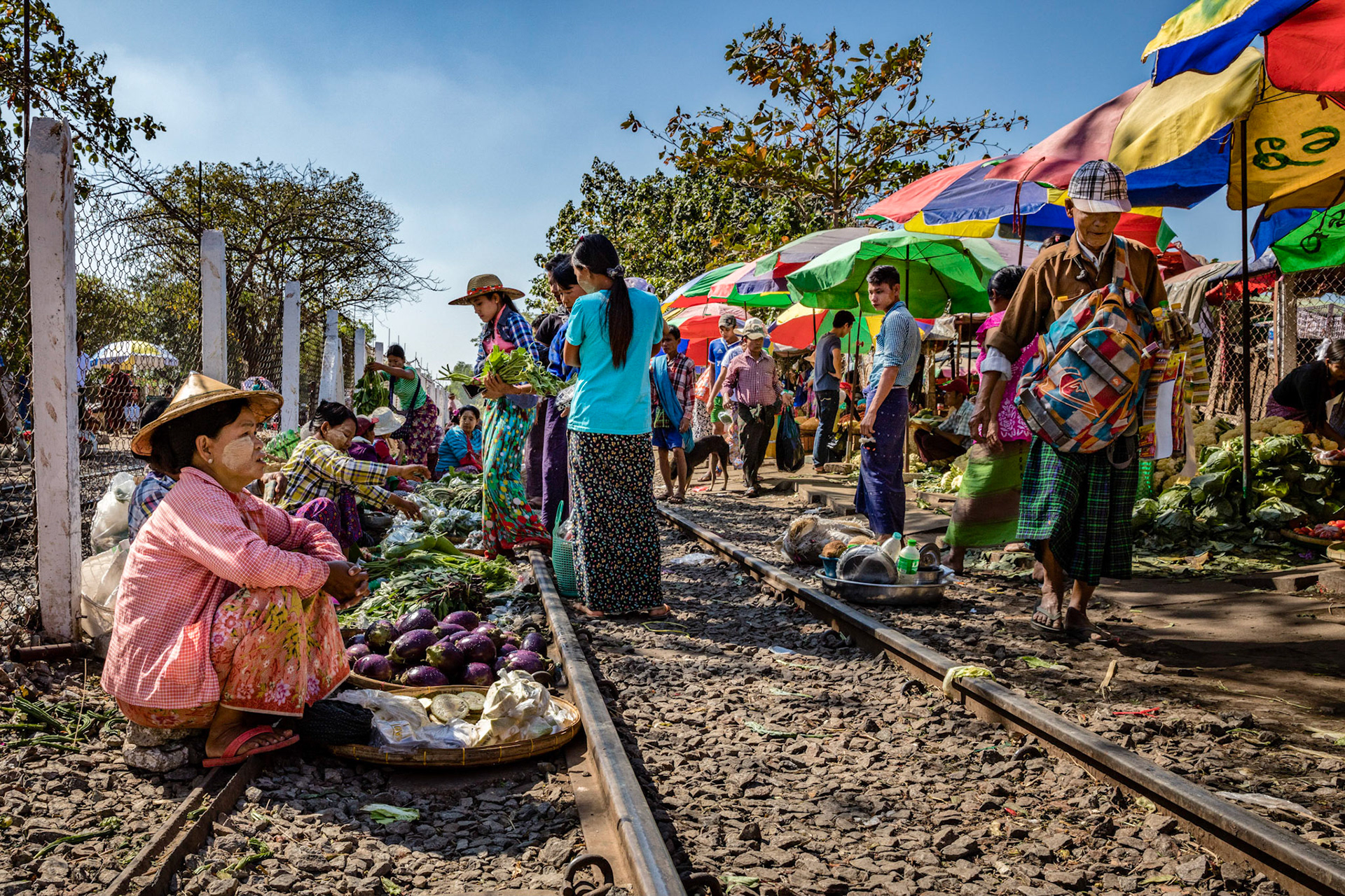 Burmese locals selling produce on the train tracks at the Da Nyin Gone market in Yangon, Myanmar.