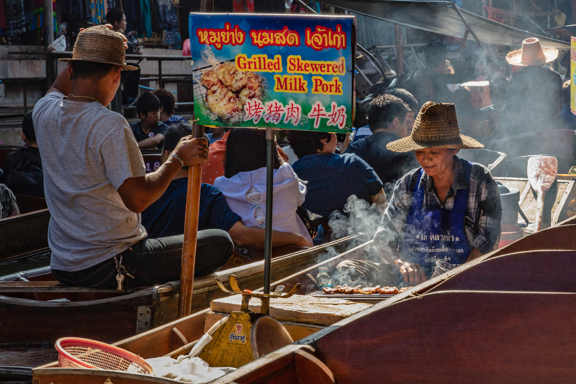 Woman making grilled pork on a boat in a floating market near Bangkok