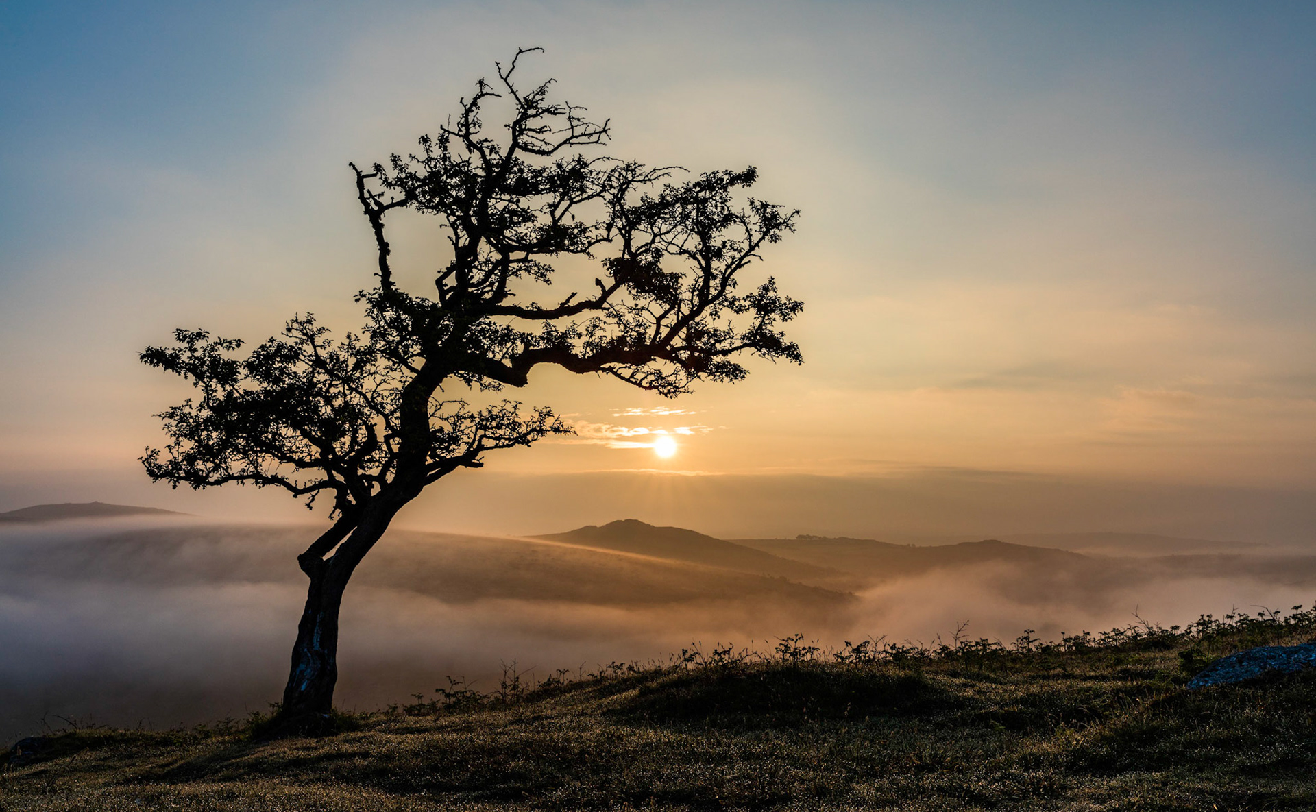 Sunrise over a hazy valley near Combestone Tor in Dartmoor National Park.