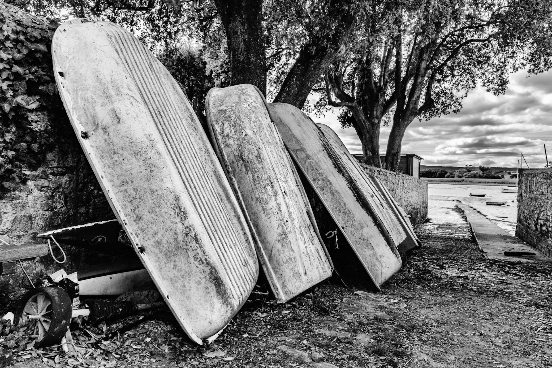 Boats leaning against an old stone wall in Topsham, Devon, UK.