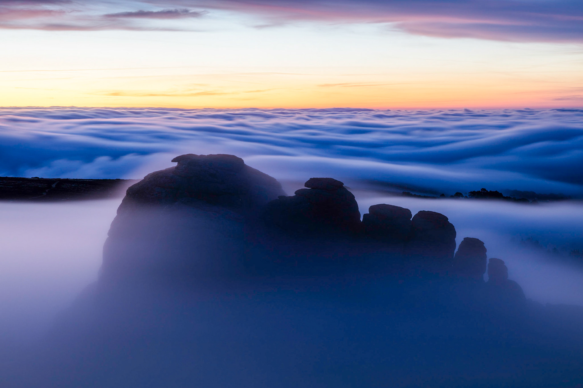 Haytor rocks emerging from the low lying clouds during blue hour in Dartmoor National Park, Devon, England.