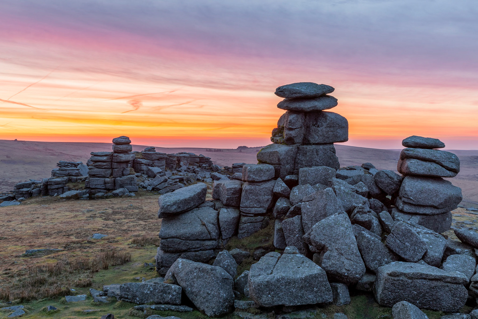 Colourful clouds before sunrise on Great Staple Tor in Dartmoor National Park.