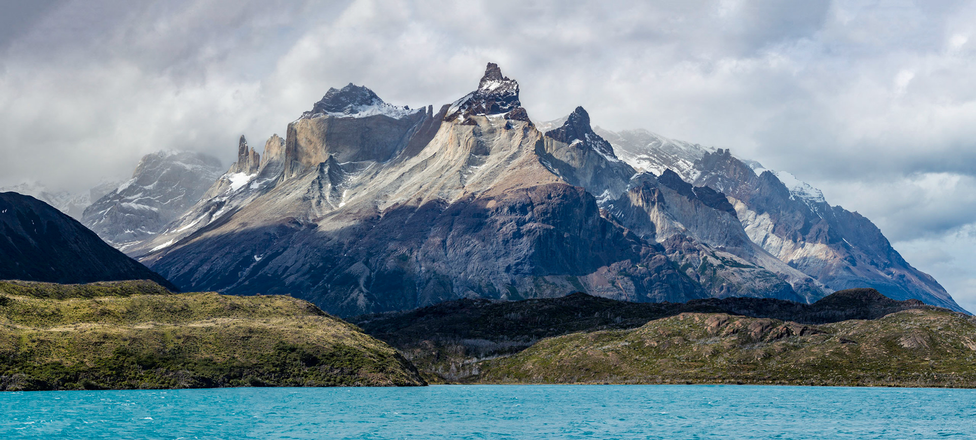 Panorama of the unique peaks in Torres del Paine national park (called horns) taken from bright blue waters of Lago Pehoe