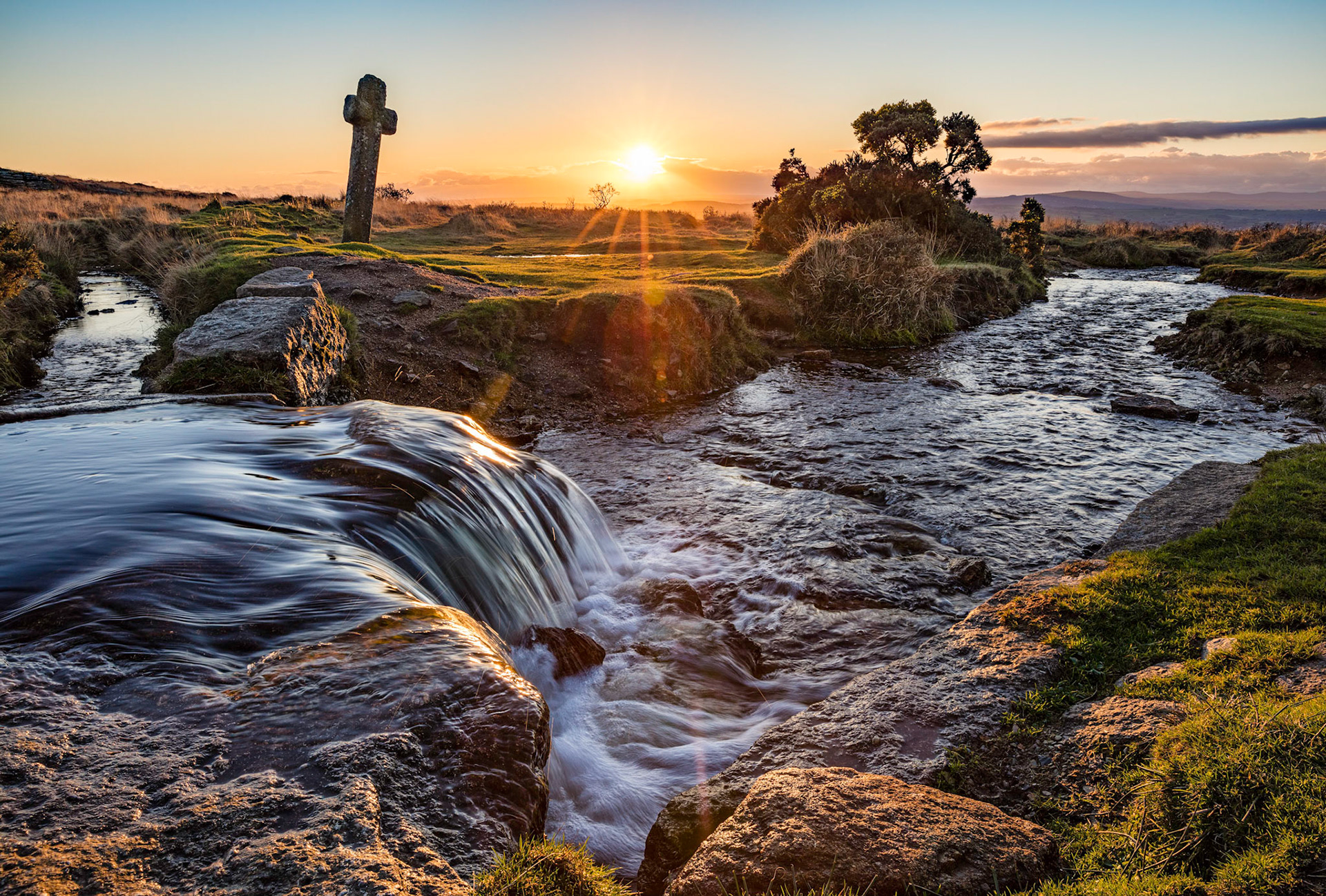 The setting sun behind the Windy Post cross and the Grimstone and Stortridge Leat.