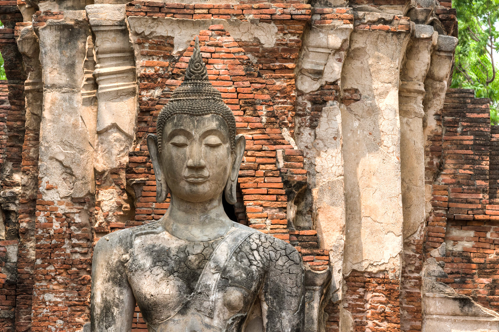 A full sitting budda statue cracking from being out in the elements at the Wat Mahathat temple in Ayutthaya, Thialand