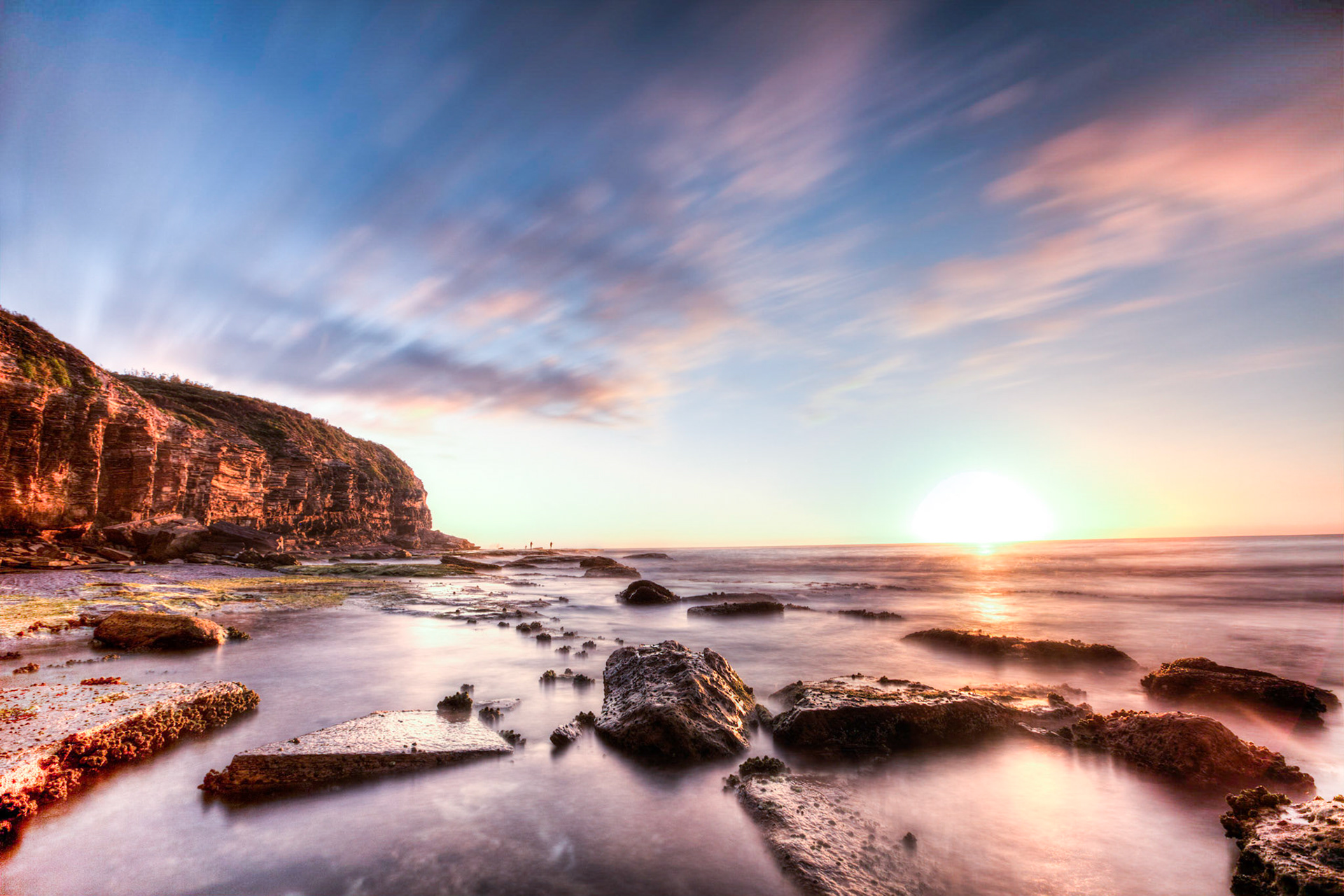 The sun hitting the eastern coastal cliffs of Australia as wave crash around me. I take the long exposure to blur the clouds and flatten the water, but you can still make out the fishermen off in the distance.
