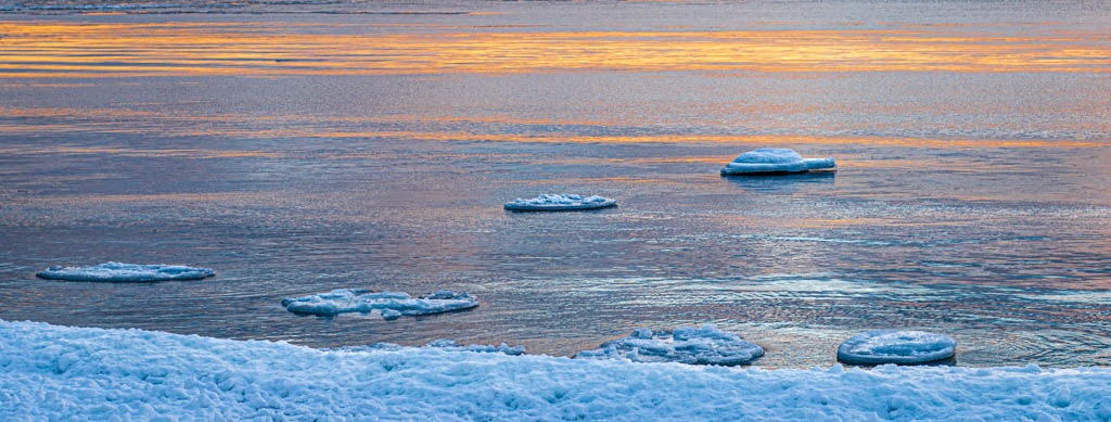 photo of open water with ice at sunset