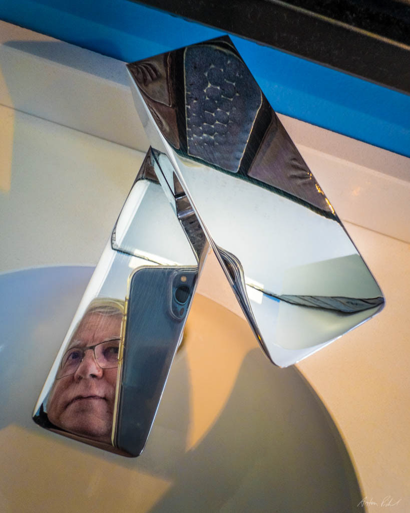 self-portrait of a reflection off a bathroom water faucet