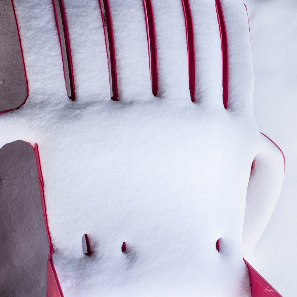 overhead photo of a plastic chair covered in snow