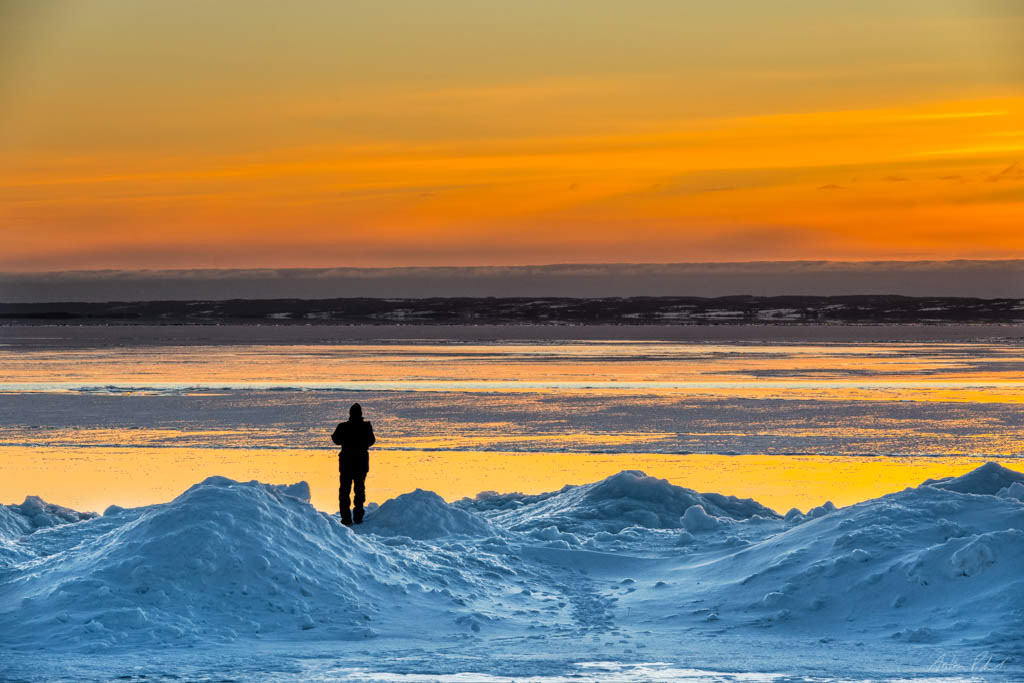photo of a colourful sunset looking over a winter scene with a man in the foreground,