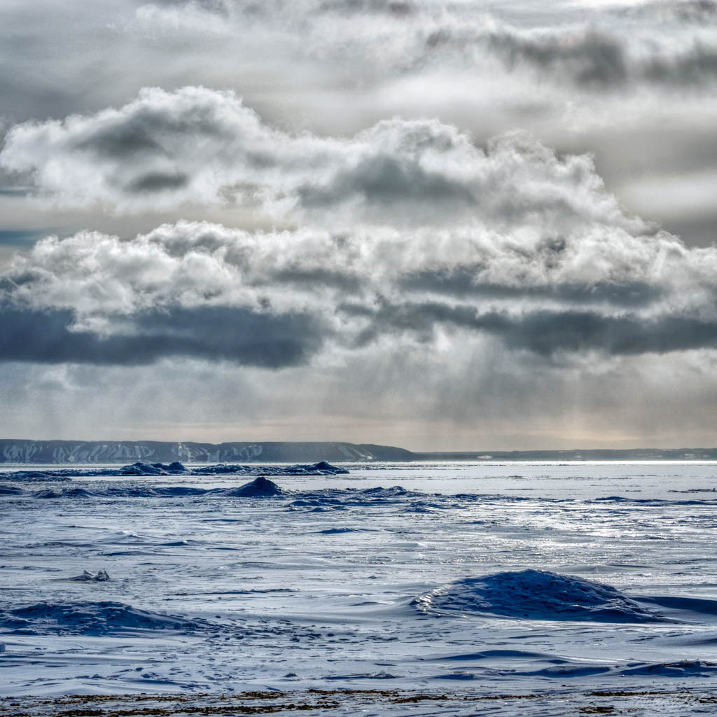 landscape photo overlooking a frozen lake with hills in the distance