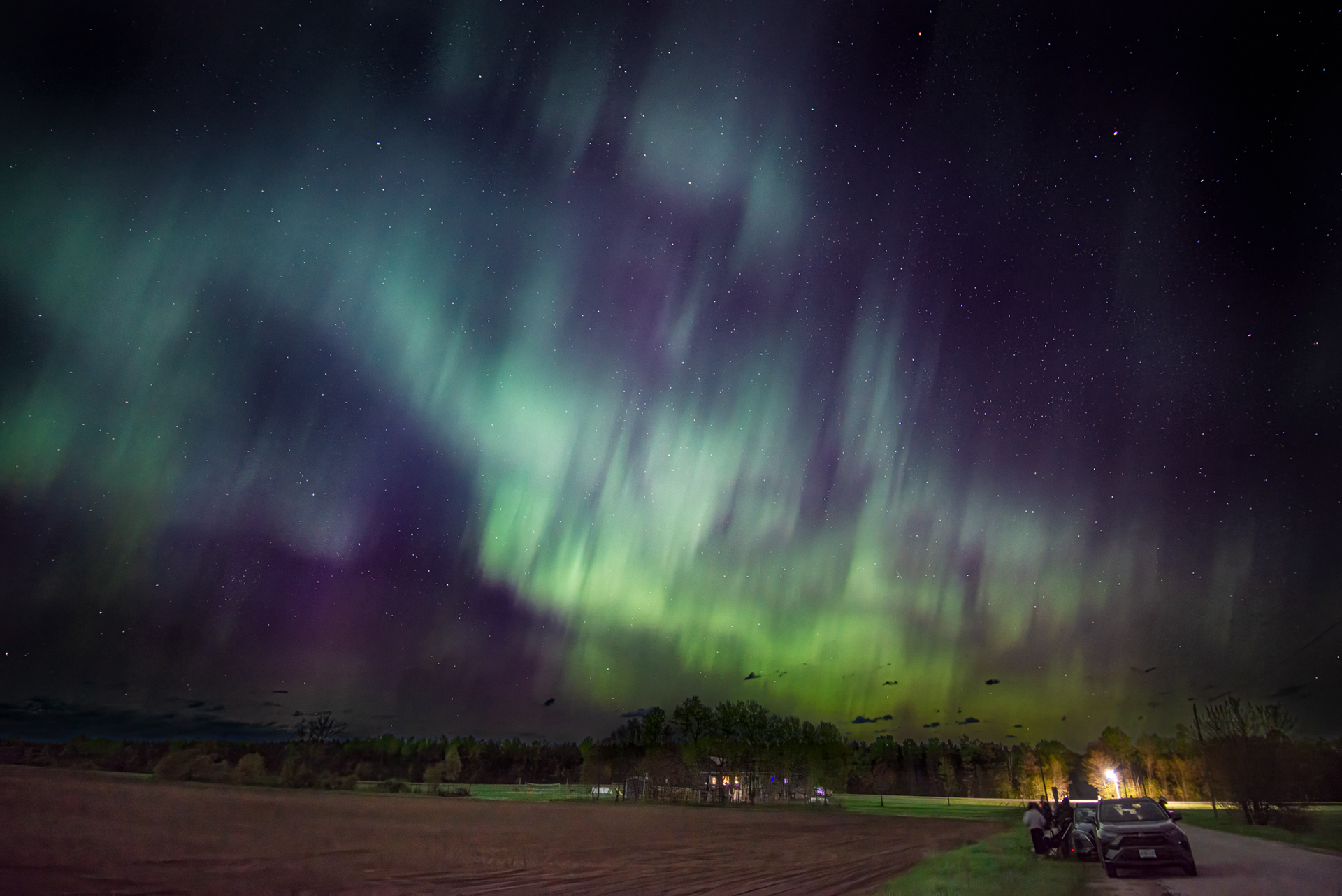 image of aurora with car in the foreground bottom left