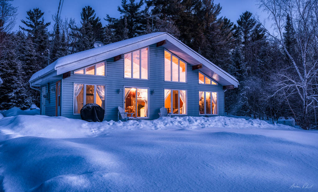 early morning photo of a house with lights on in winter