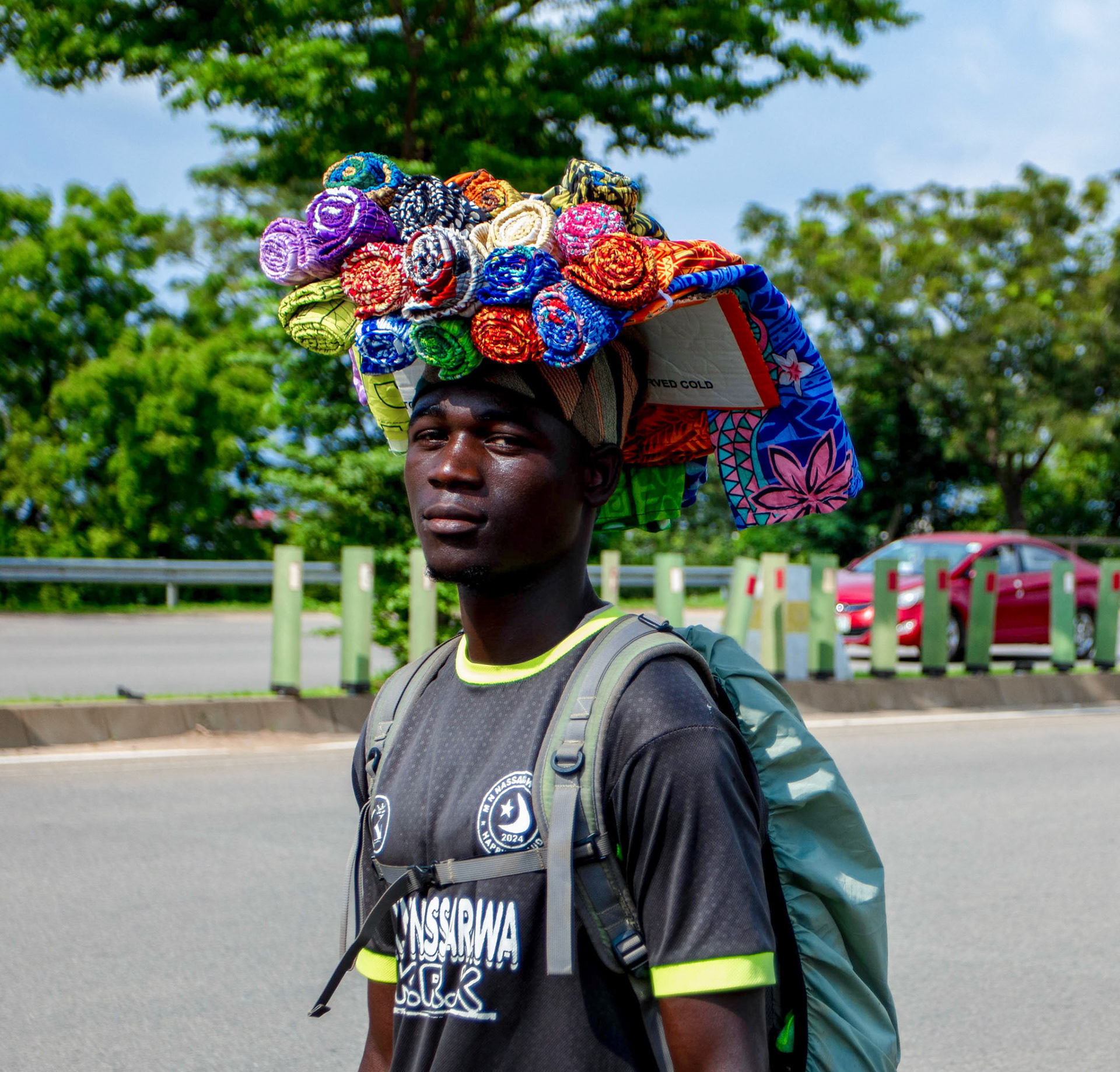 A street vendor carries a vibrant collection of textiles, turning everyday goods into a visual expression of labour, movement and livelihood.