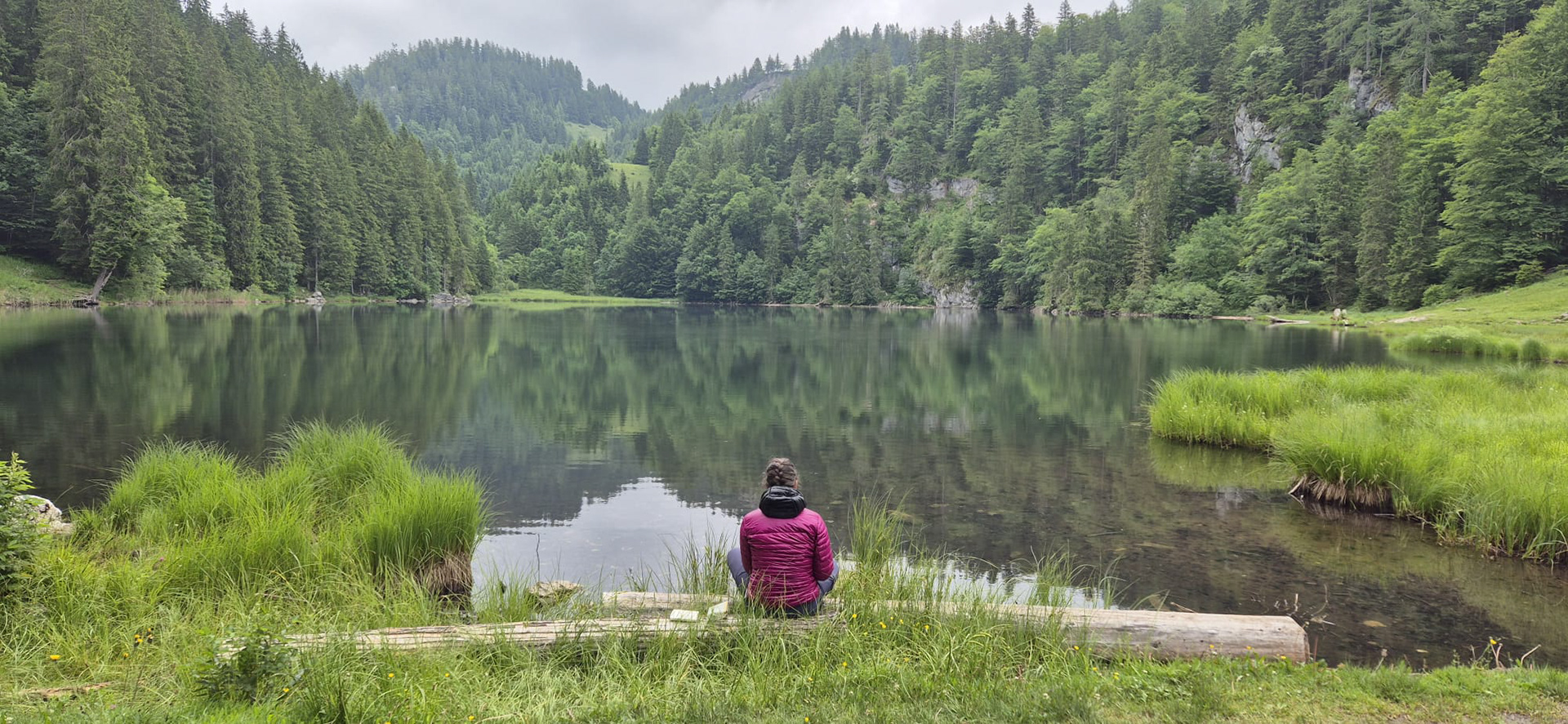 une photo de lea en train de dessiner au bord d'un lac de montagne lors d'un stage rando croquis en autriche 