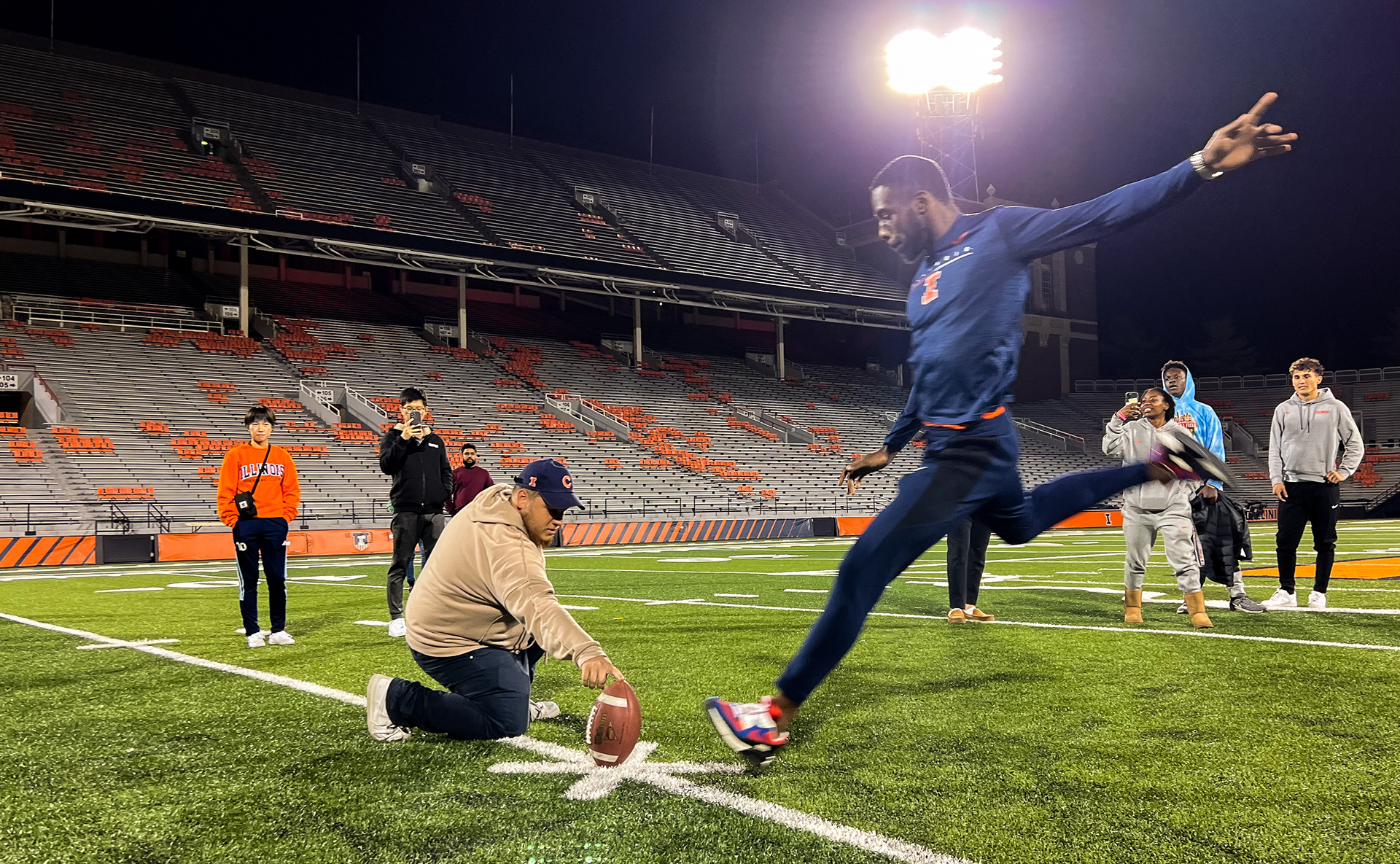 Kashief King, a track and field runner from Trinidad and Tobago, takes a shot at kicking a field goal after the presentation concludes. The Fighting Illini Athletic staff allowed students and athletes to take turns at field goals, throws and catches.