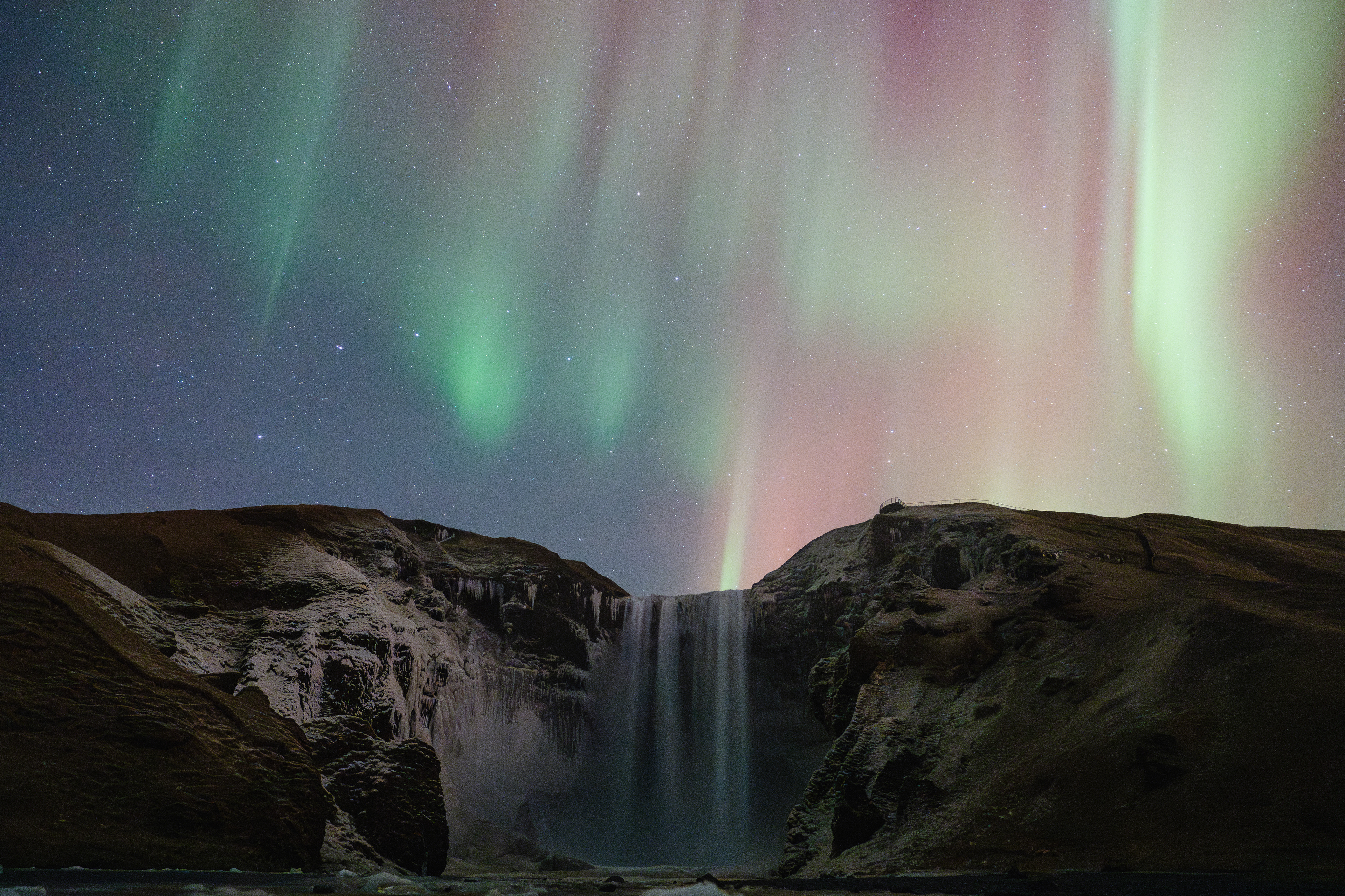 The Northern Lights dance over Skógafoss waterfall in Iceland