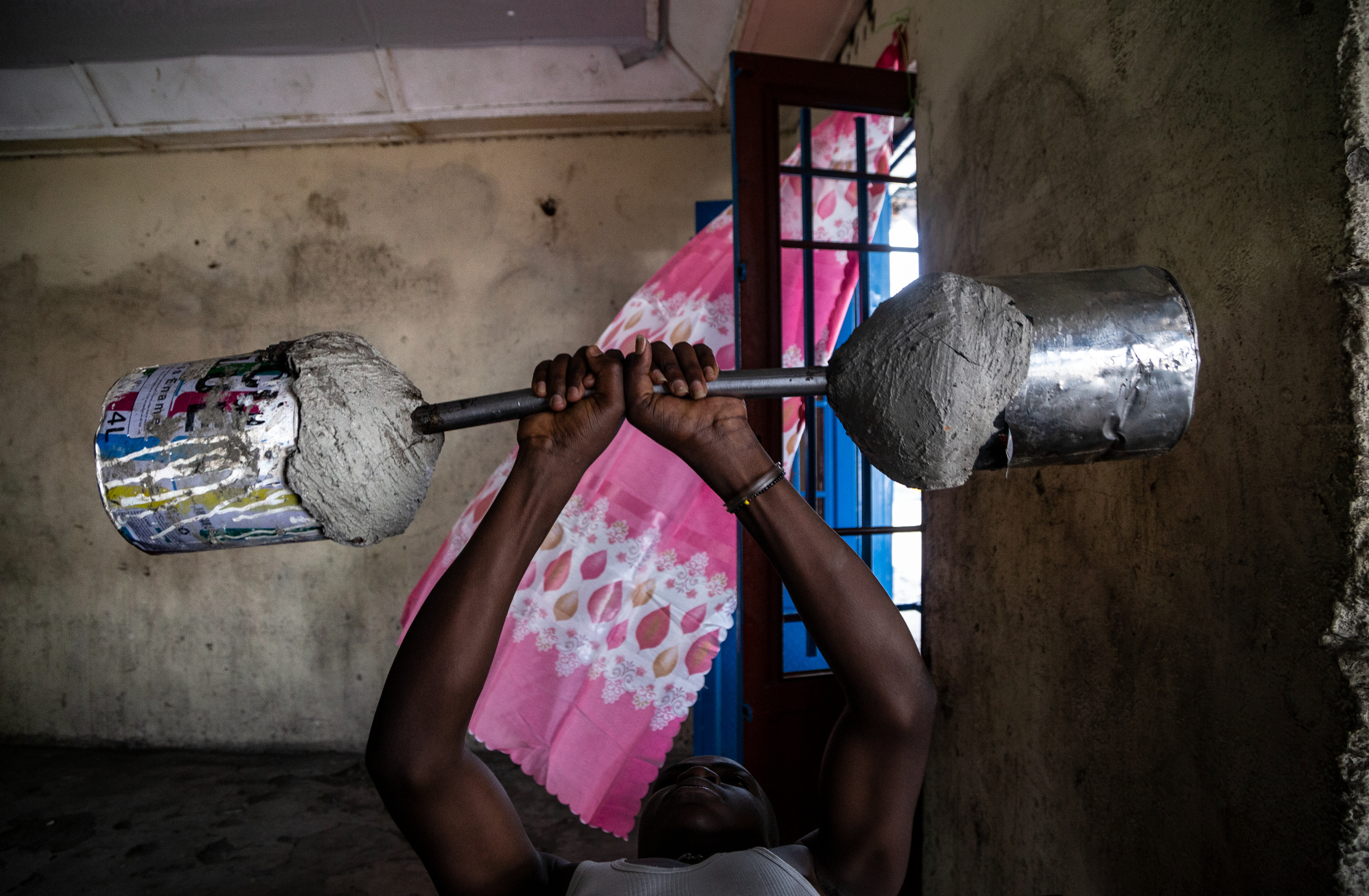A youth pumps iron  with a home-made barbell n one of the dormitories at the CTO CAJED in Goma.