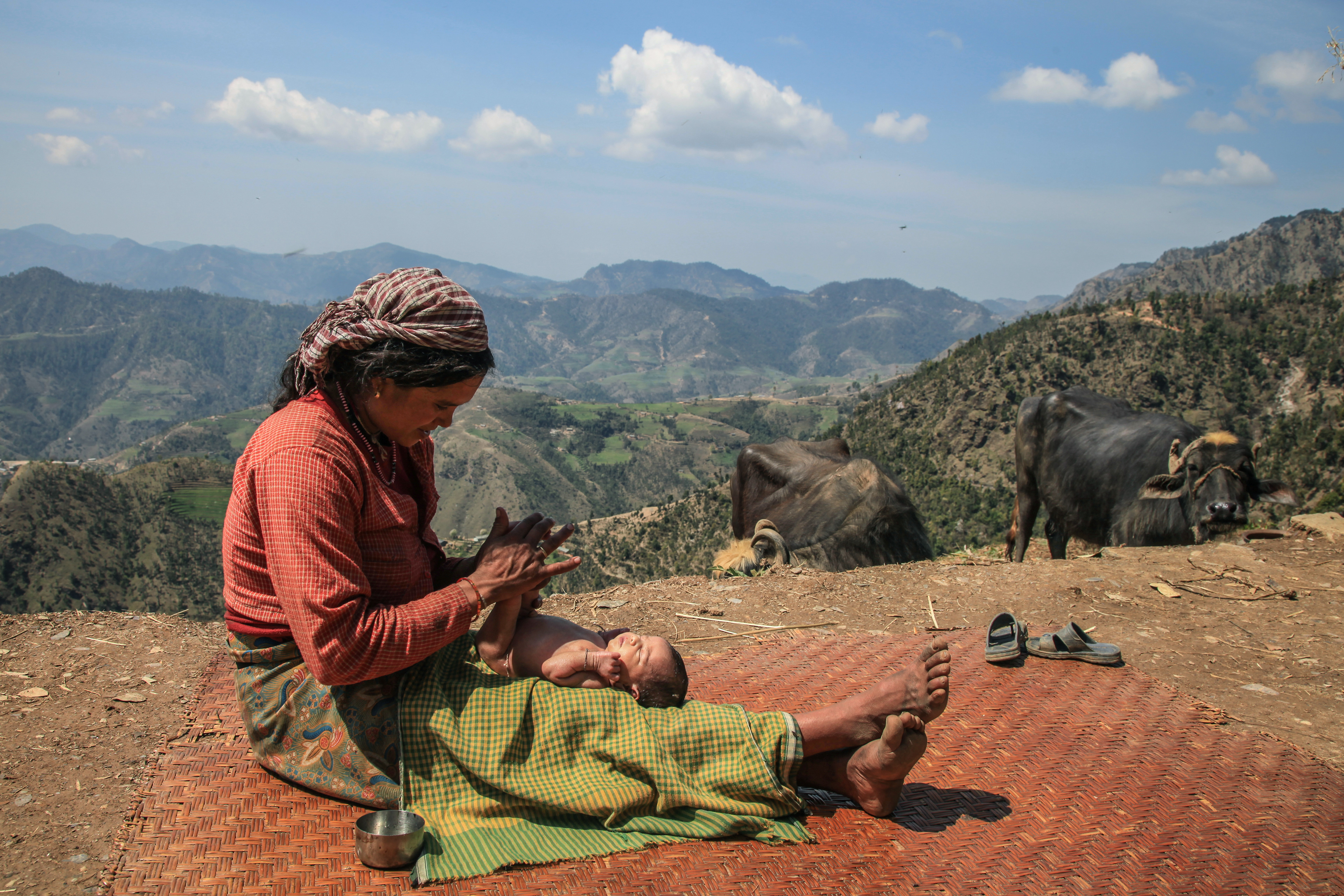 A mother applies oil to the skin of her newborn outside her home in the mountains of Western Nepal. The Baby was delivered at the Gazari birthing Center. March 2015