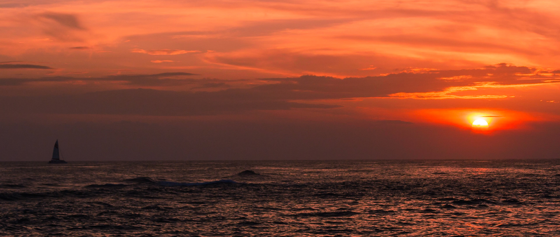 On a gorgeous evening on the island of Kauai, this catamaran sails towards the setting sun.