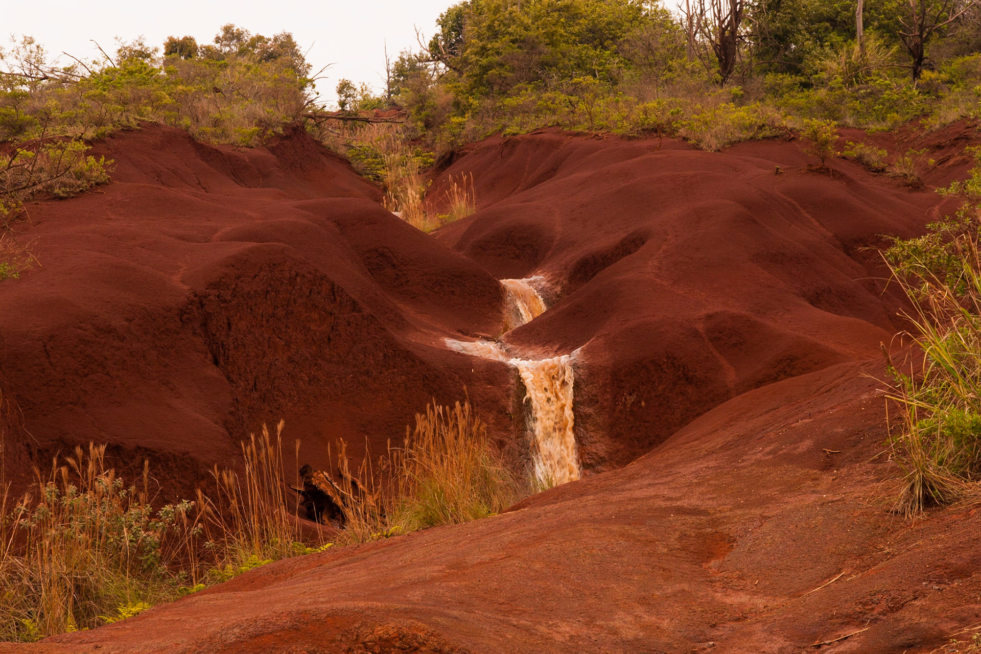 This waterfall cuts through the cool volcanic red landscape of Kauai mountain.