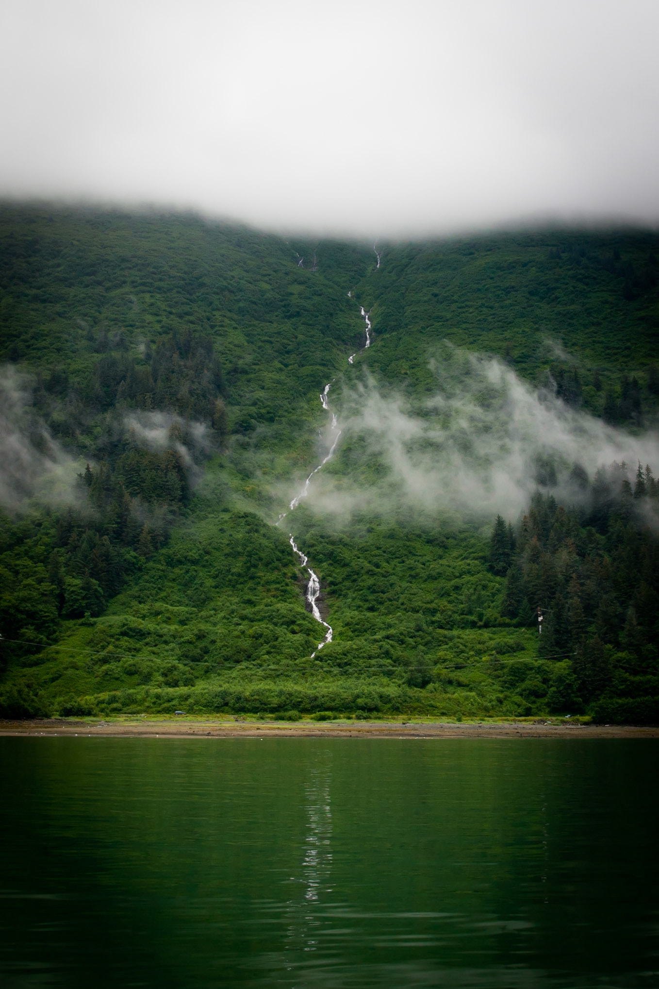 Thin waterfall coming out of the low clouds into the Icy Straights of Alaska.