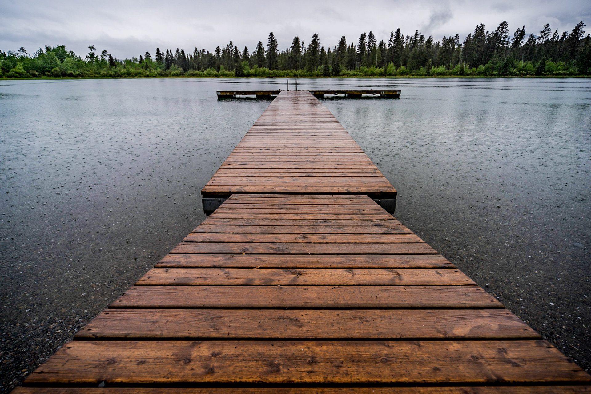 A wet dock, empty lake on a rainy day at Norbury Lake, British Columbia.