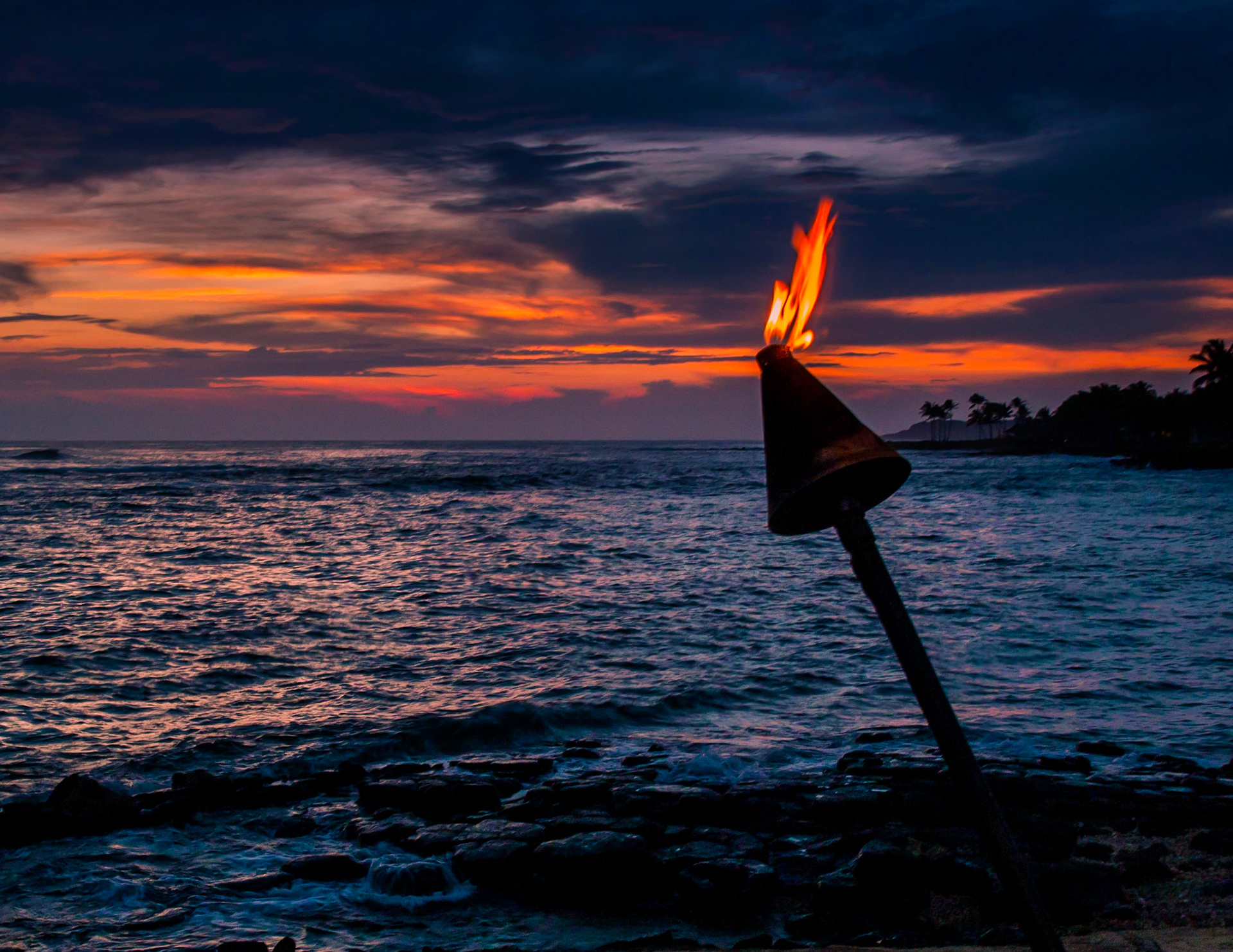 This lone torch is perched on the edge of the ocean as the sun sets in Kauai, Hawaii.