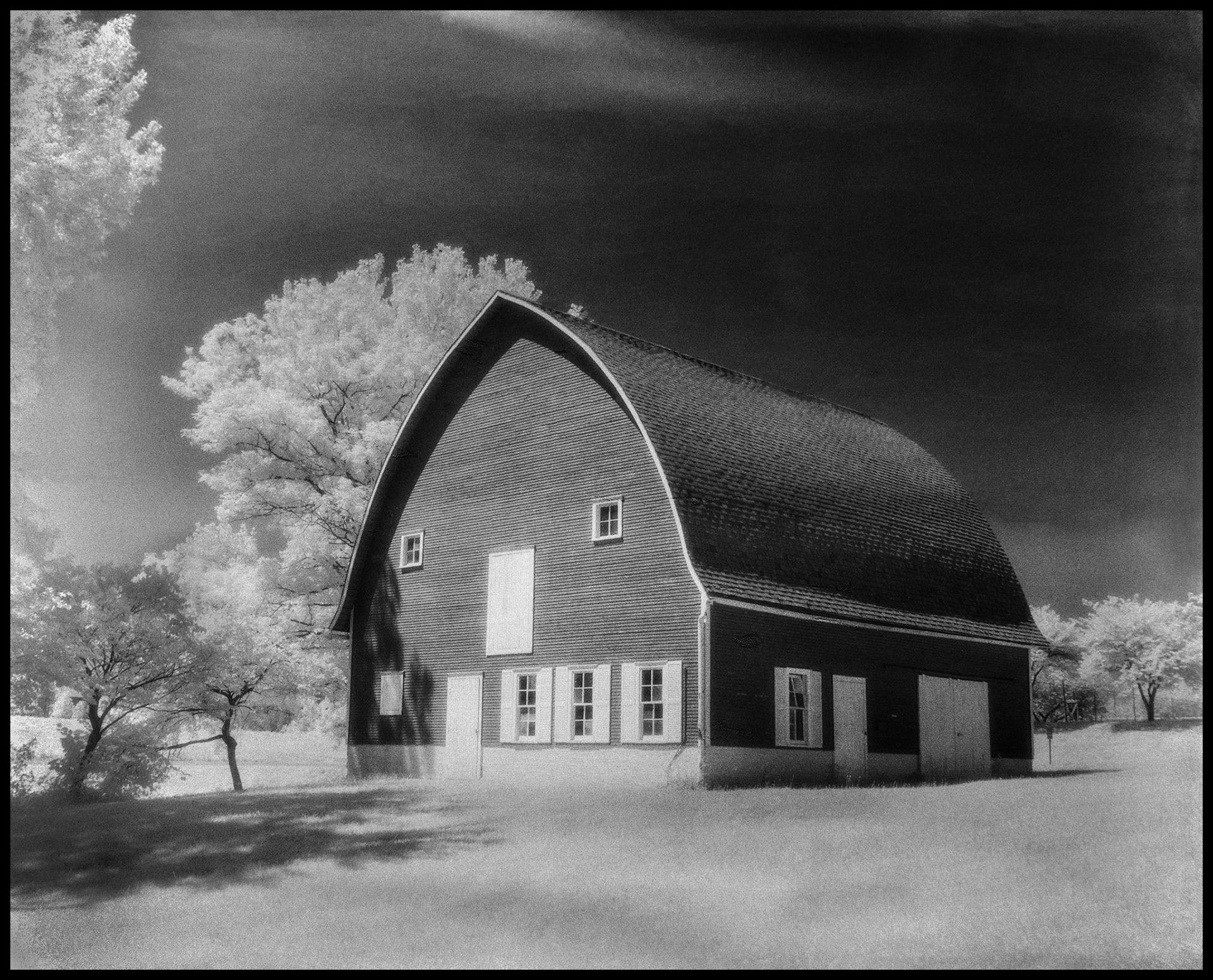 A vintage black and white infrared view of the Red Barn in Red Barn Park on the (NMSU) Truman State University Campus in Kirksville, Missouri. An ongoing local art fair was named after this barn as it started in this park in 1974. 1982