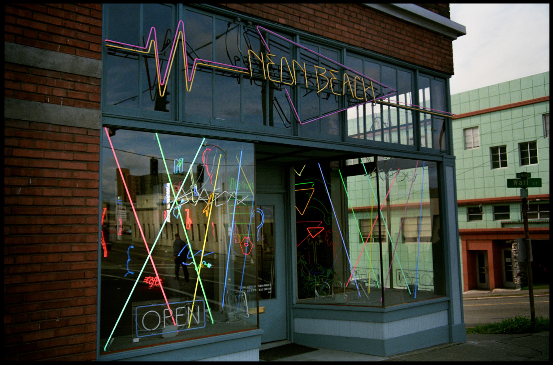 A vintage street scene of the colorful neon signs and the reflecton of a man in the window of a neon sign store  at the corner of First Ave and Wall St in Seattle, Washington, USA 1987