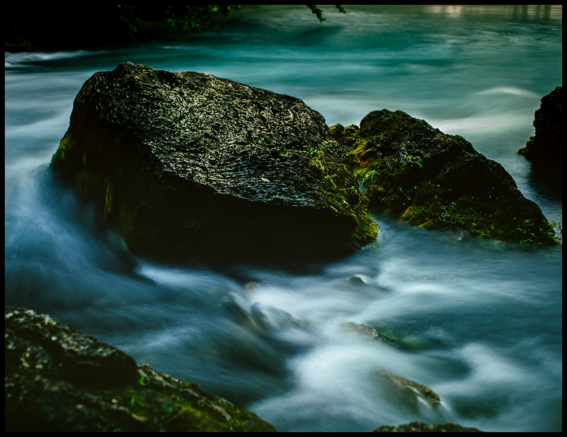 A vintage, moody, soft focus view of the water flowing around a big boulder at the outet of Big Spring near Van Buren, Missouri. Part of the Ozark National Scenic Riverway. 1982