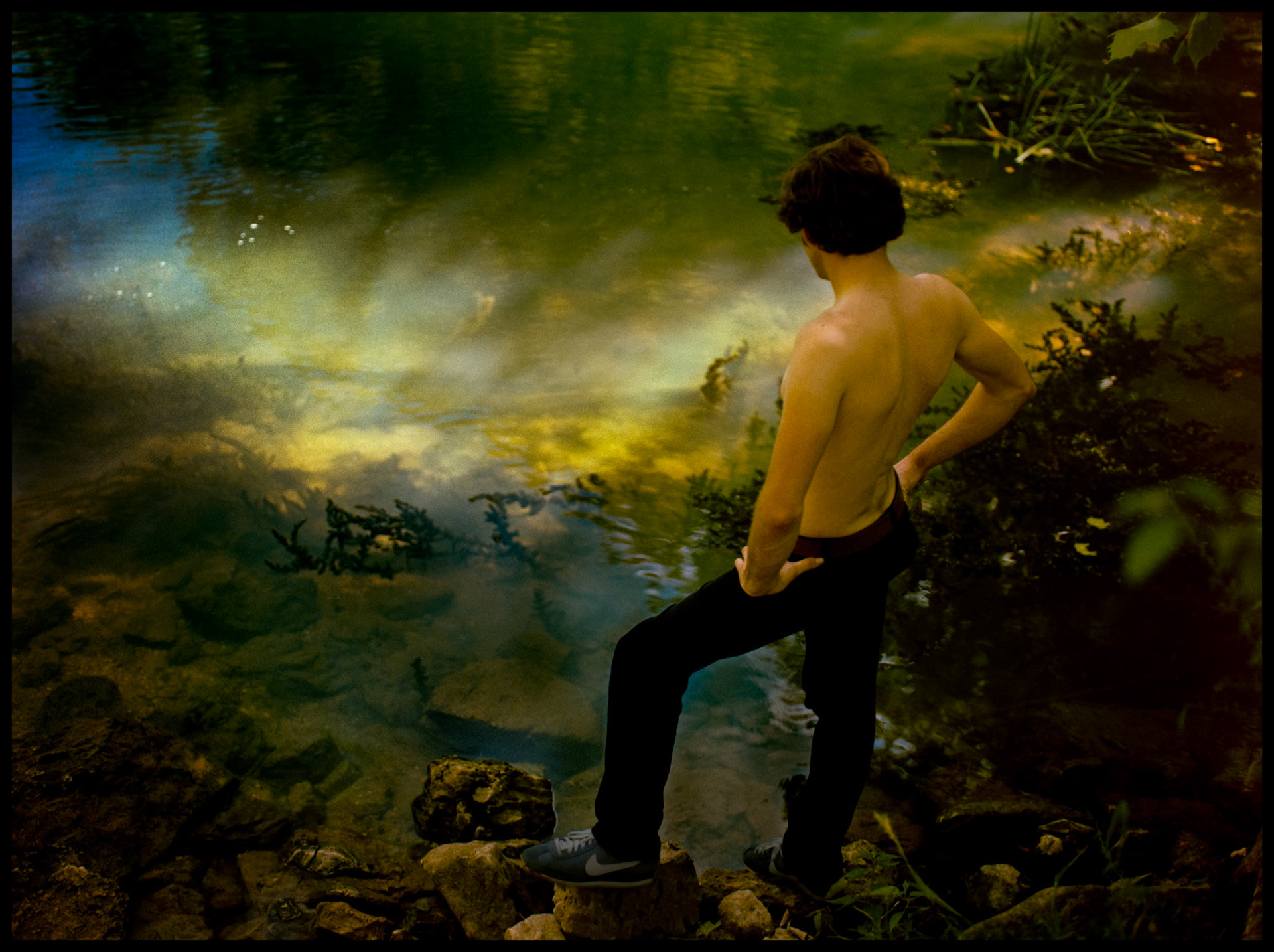 A soft focus image of a young man gazing reflectively into a sunlit spot in a clear water stream at Lake Of The Ozarks State Park near Osage Beach, Missouri 1982