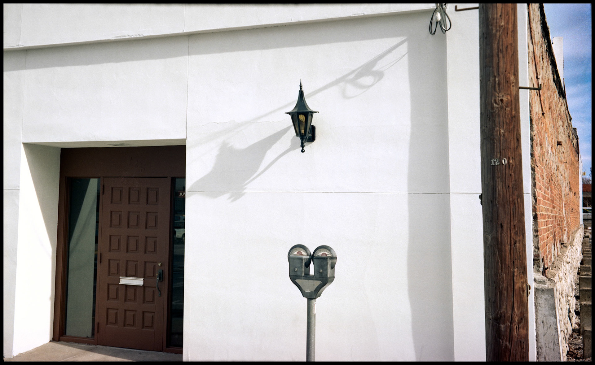 Interesting abstract detail of the white stucco front of a commercial building, a parking meter, and decorative light. Columbia Missouri 1989