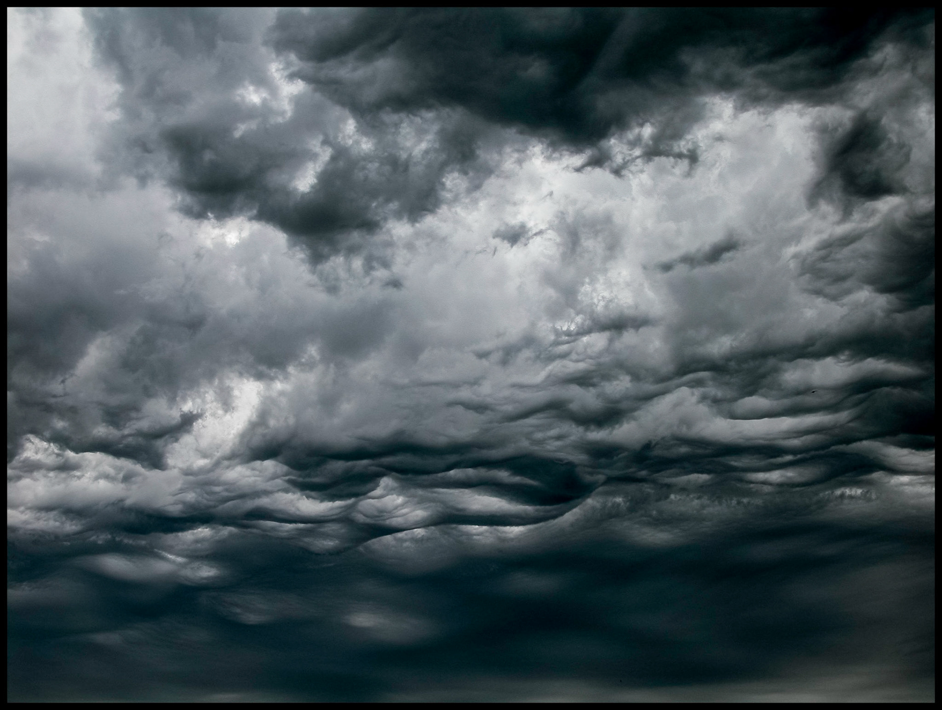 Menacing looking storm clouds with cirular openings of light shining through resembling a face.