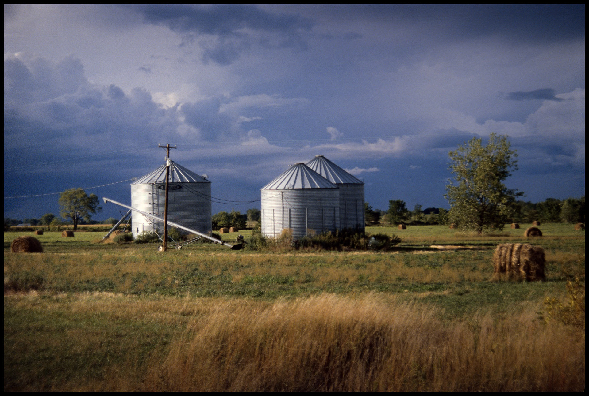Grain Bins, near Millard Missouri with ominous storm clouds approaching in background, 1988
