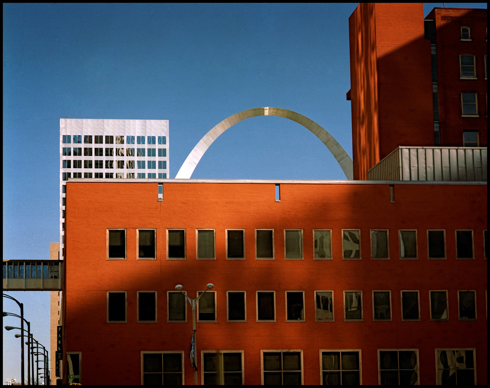 A vintage minimialistic abstract urbanscape detail view of a red brick offfice building obscuring most of the Gateway Arch in St. Louis, Missouri USA, 1988.