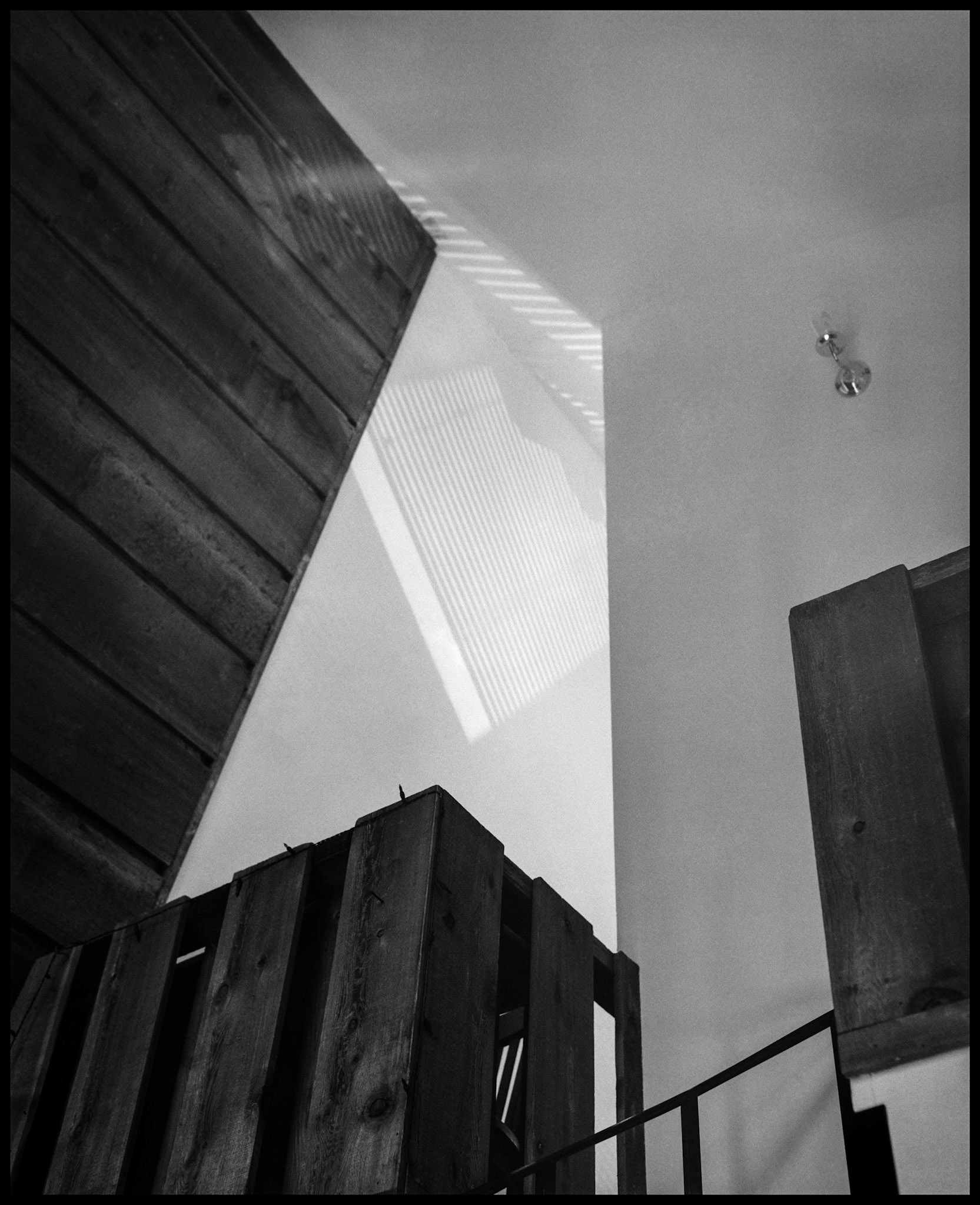 A black and white minimal abstract composition of afternoon highlights and shadows on the interior wall of an A-Frame house. Near Rocheport, Missouri 1993