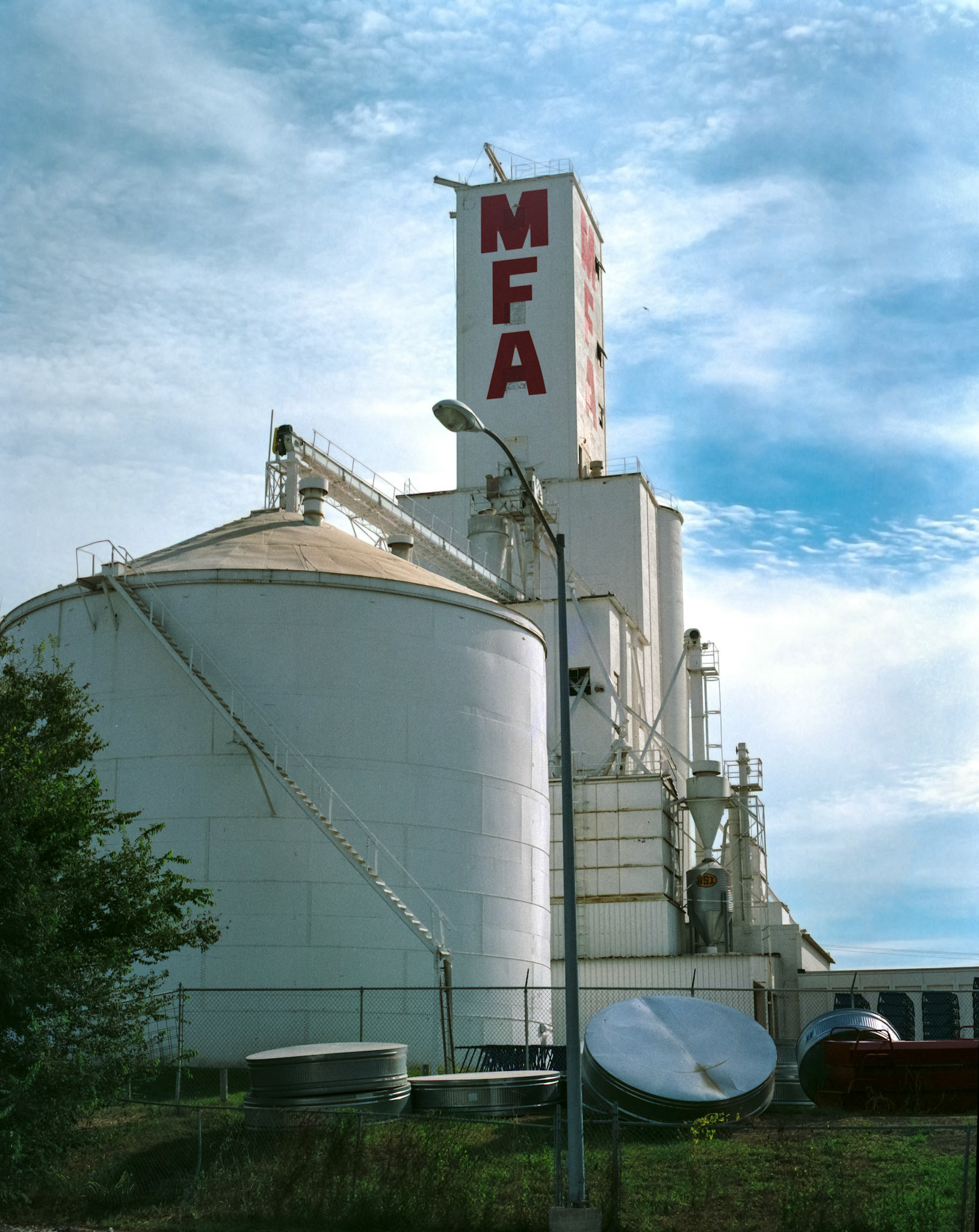 An MFA Coop grain elevator and storage silo against a sky with light clouds in Columbia, Missouri USA.