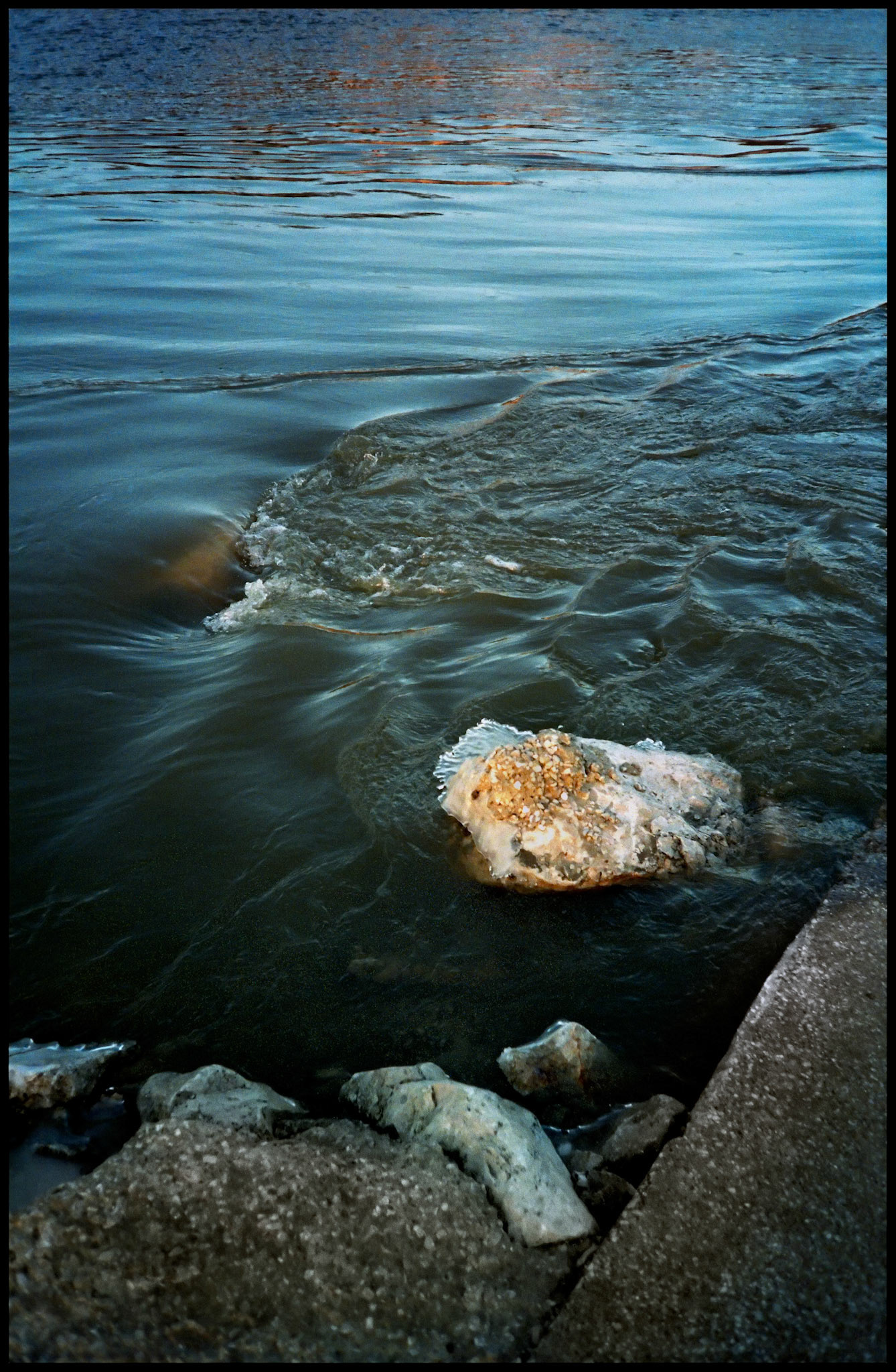 Ebb and flow of water around a boat ramp and stones with reflections of a bluff at the edge of the Missouri River near Rocheport, Missouri 1992