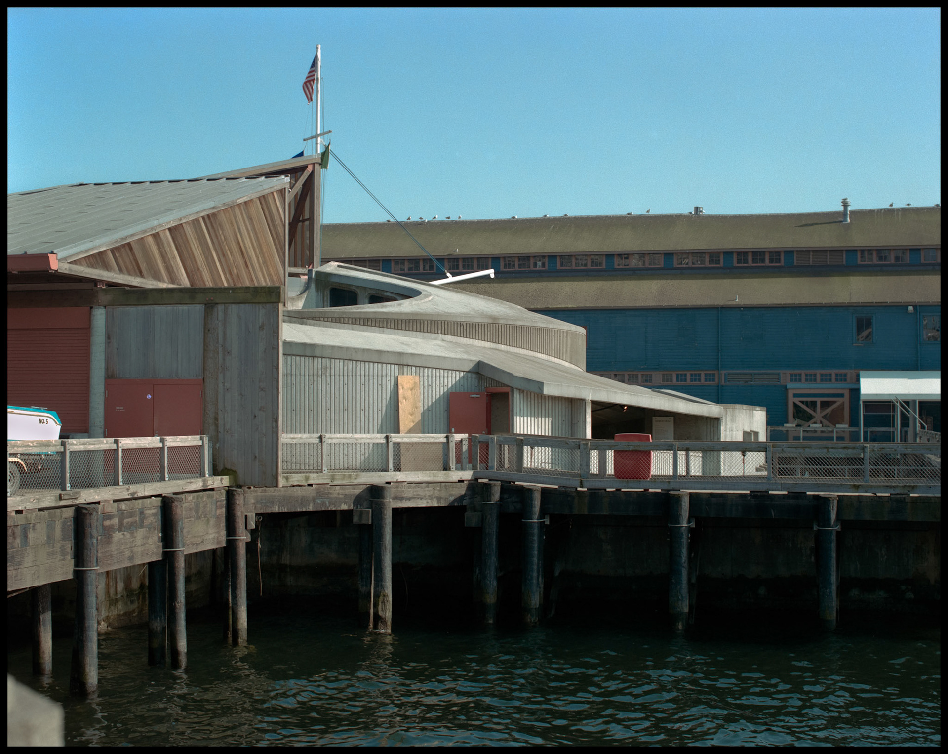 A vintage waterside view of the building that is now the Seattle Aquarium from an adjacent pier. Seattle Washington USA 1987