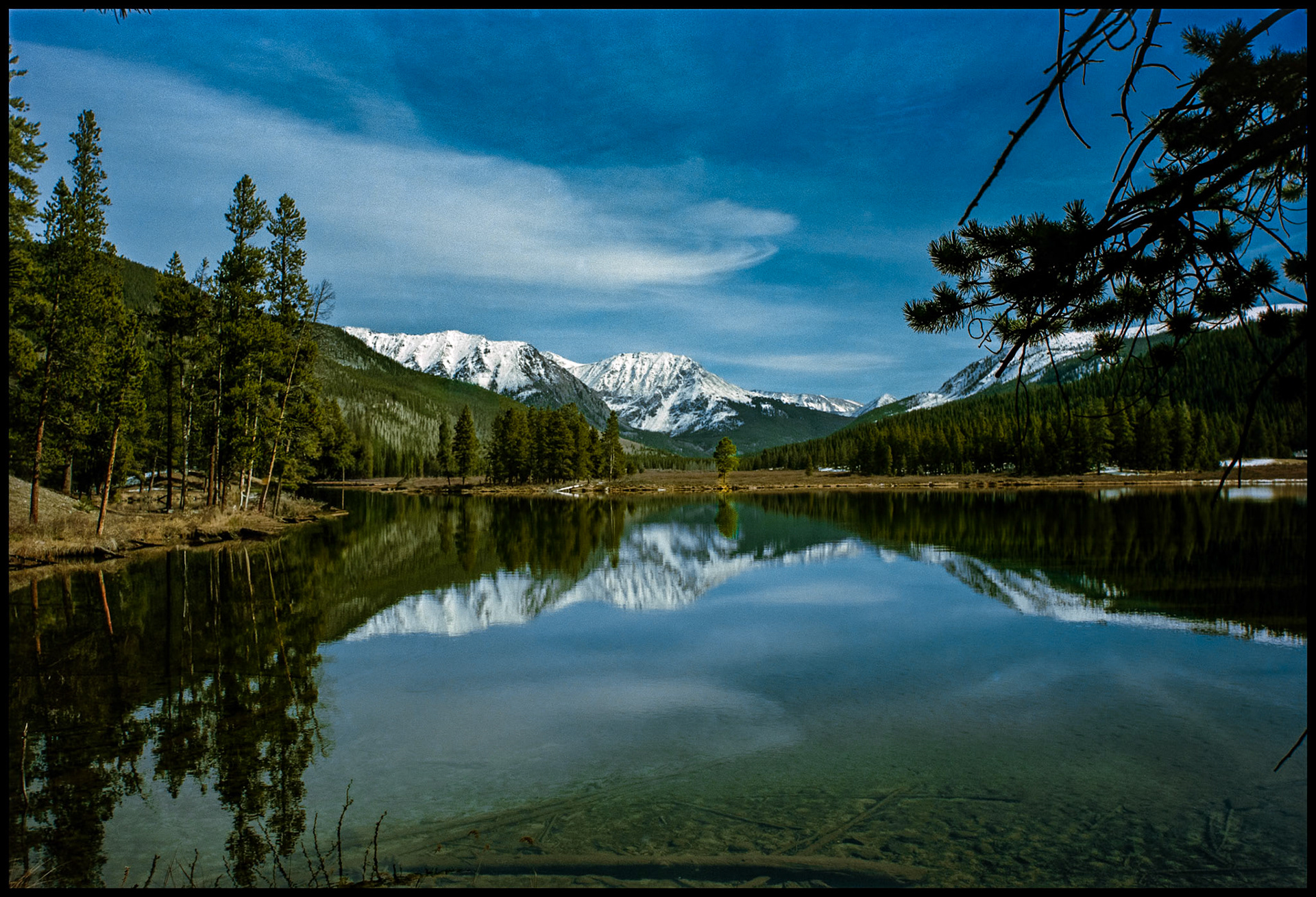 A view of the snowcapped Collegiate Peaks area in the Sawatch mountain range from the shore of one of the Texas Lakes in Taylor Park near Tincup, Colorado USA