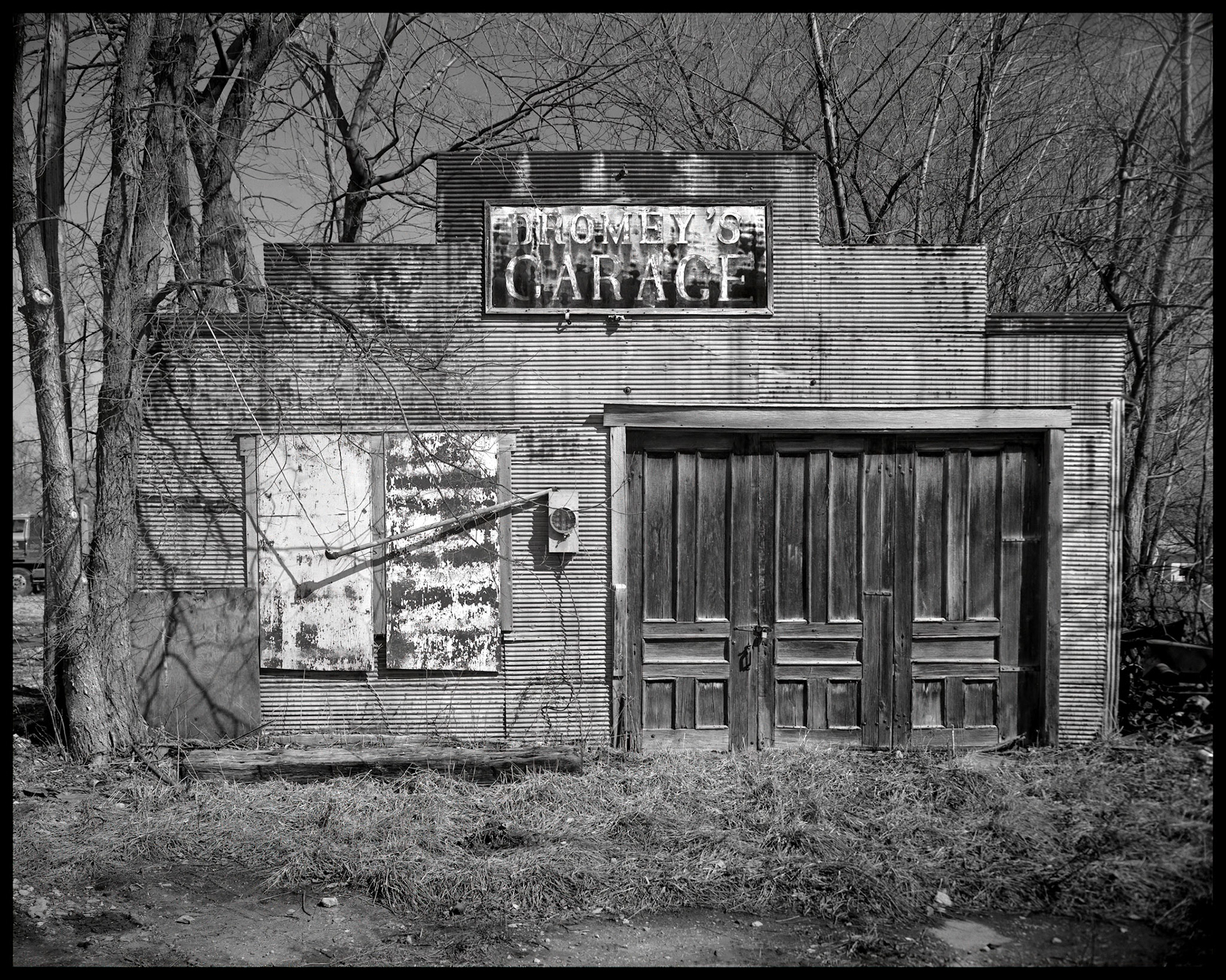 An abandoned metal building with wooden doors and boarded up windows that once housed Dromey's Garage. Baring, Missouri, 1988. Part of my Lost Baring series.