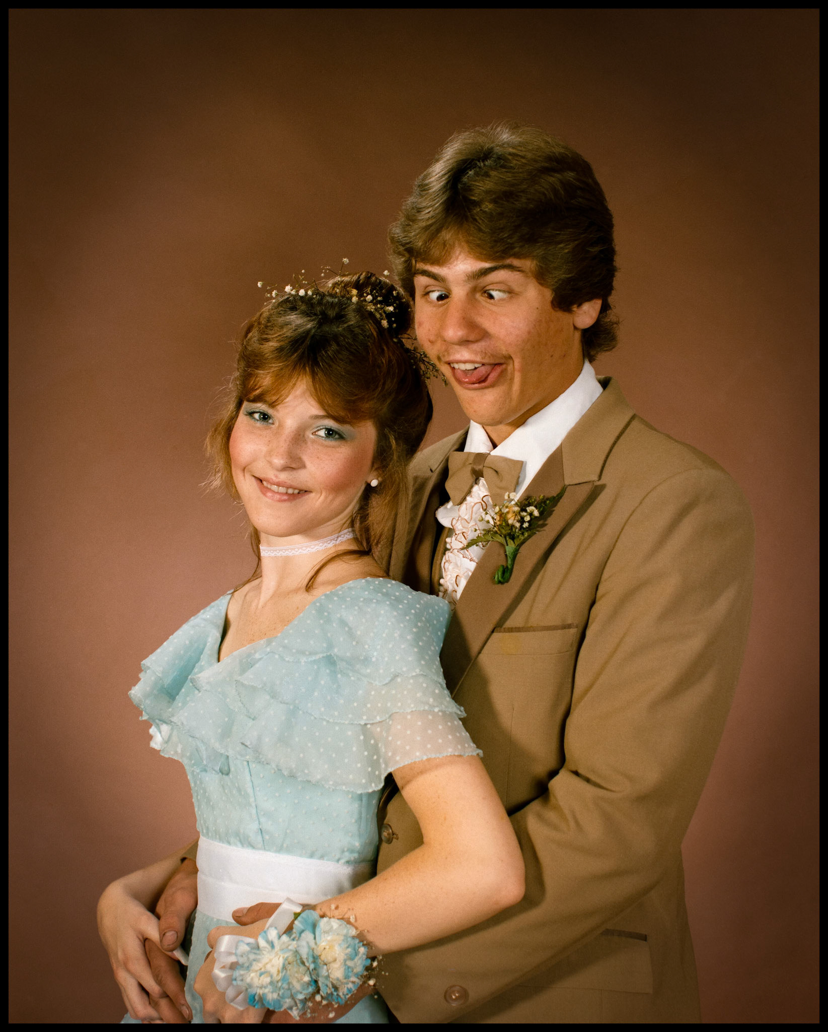 A whimsical vintage High School prom portrait with the unsuspecting girl looking very sweet and the boy being very silly. Kirksville, Missouri 1985