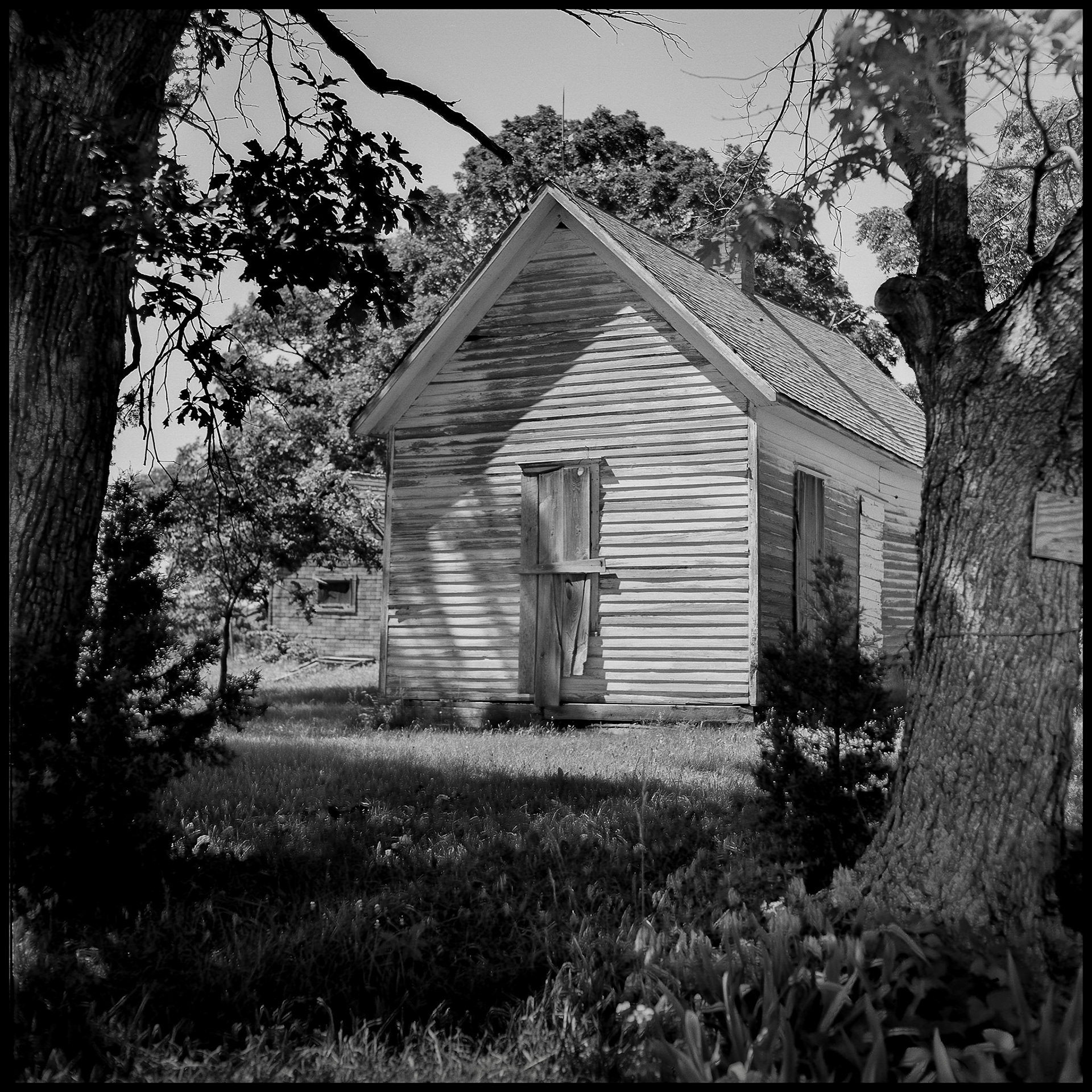 A black and white image of a boarded up rural one room schoolhouse. Near Pure Air, Missouri USA, 1977.