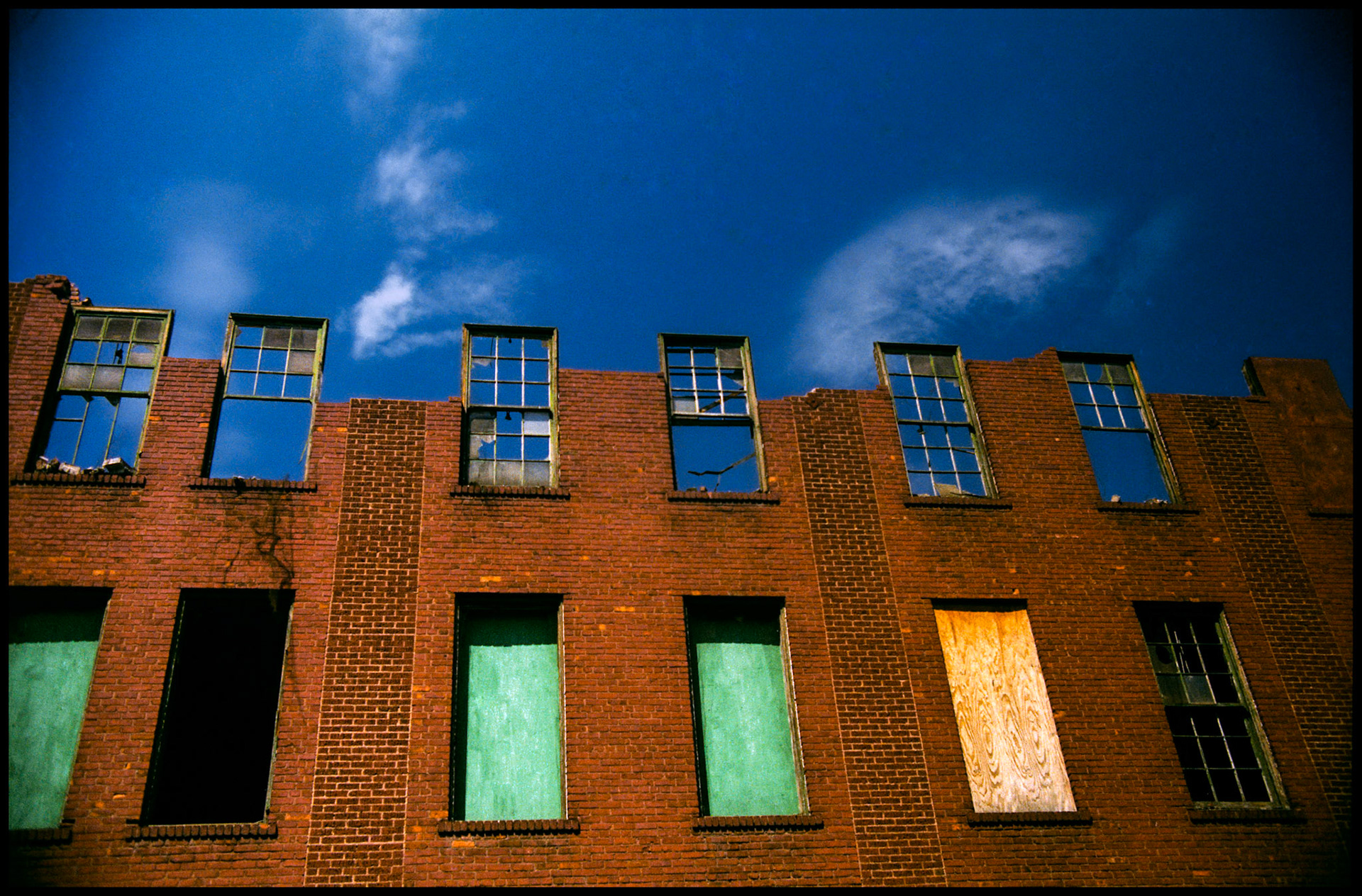 A minimal abstract urbanscape of a partially demolished building with windows protruding above the missing wall and roof. Kansas City, Missouri 1990