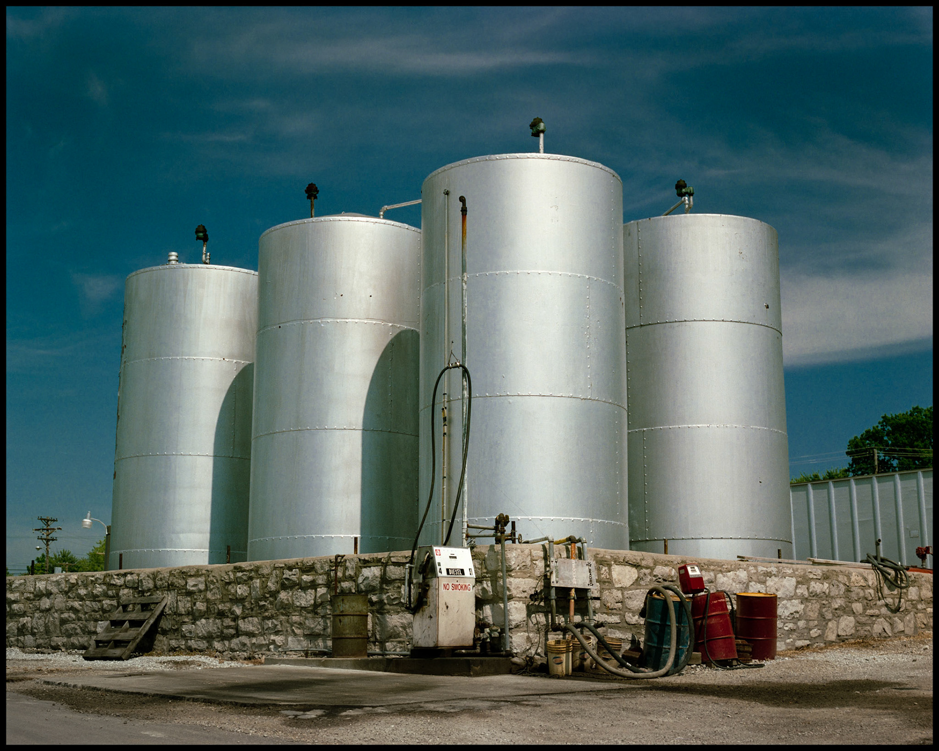A group of silver fuel tanks highlighted by the afternoon sun with a diesel fuel tank in the foreground. Columbia, Missouri 1988
