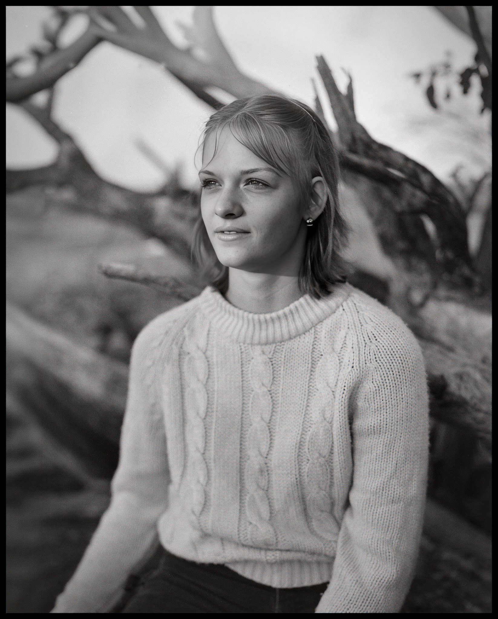 A young woman posed in front of a fallen dead tree catching the evening light just right. Near New Boston, Missouri, 1980.