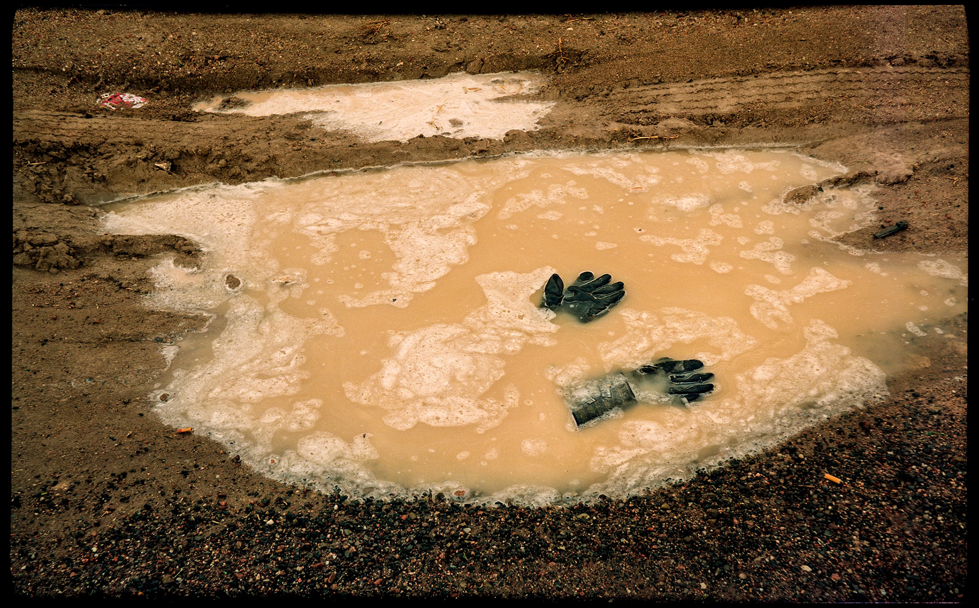 A mysterious conceptual image of lost gloves in a puddle next to a highway outside Santa Fe, New Mexico 1993