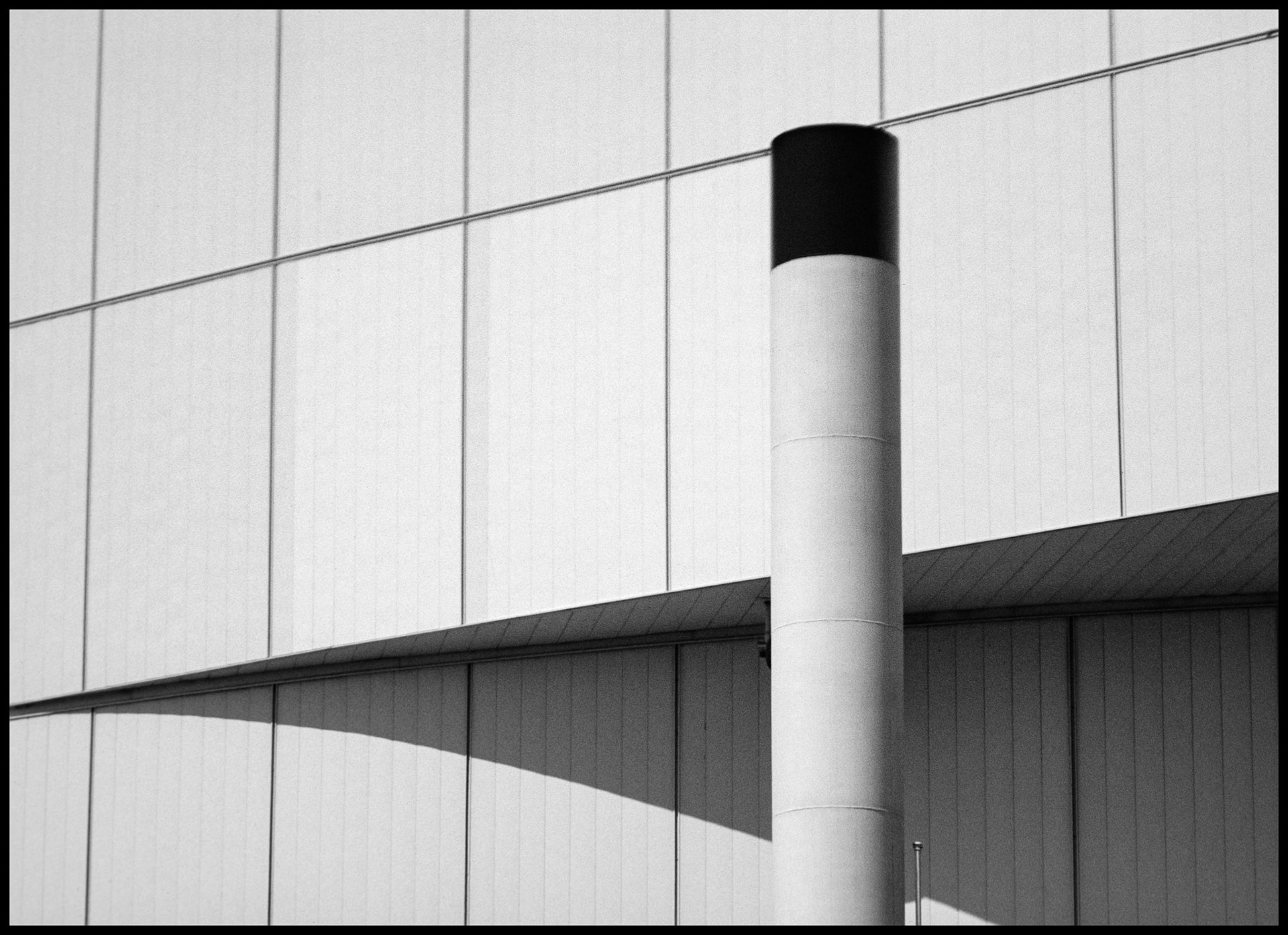 A minimal abstract urban detail of a smokestack next to the Kemper Arena in Kansas City, Kansas. 1985